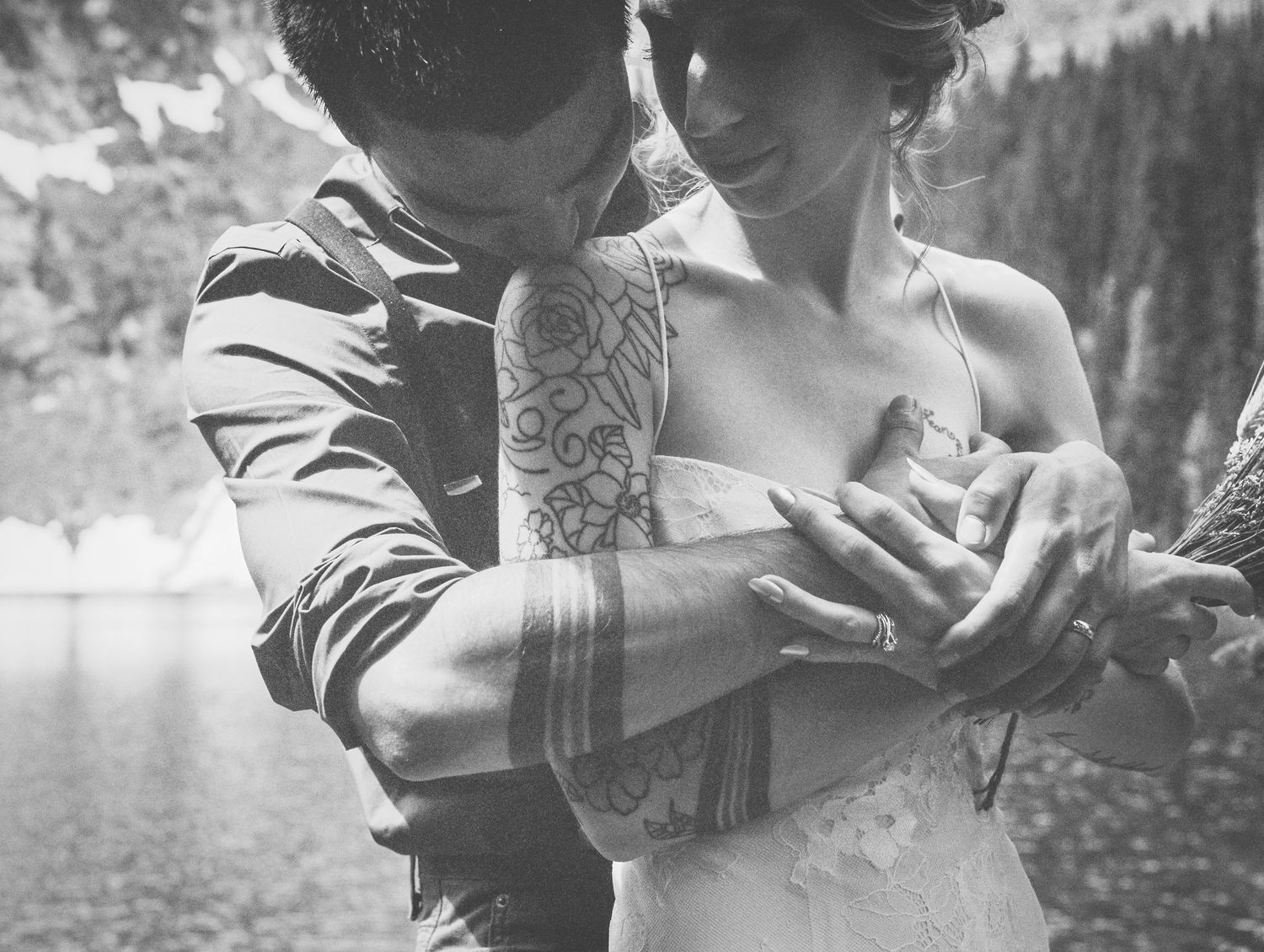 Close-up of couple's hands with visible tattoo sleeve during intimate moment.