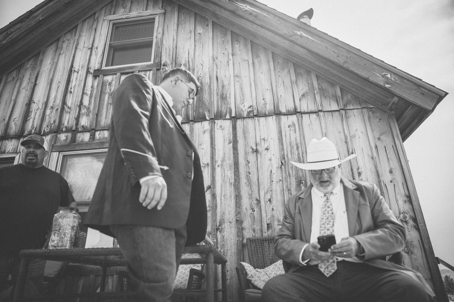 Vintage black and white photograph of a wooden house exterior with figures standing near a doorway.