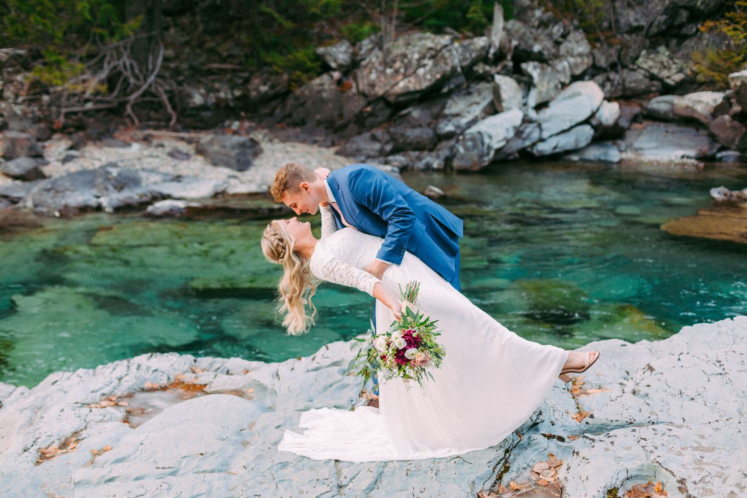 A couple poses for romantic photos by turquoise waters and rocky cliffs.