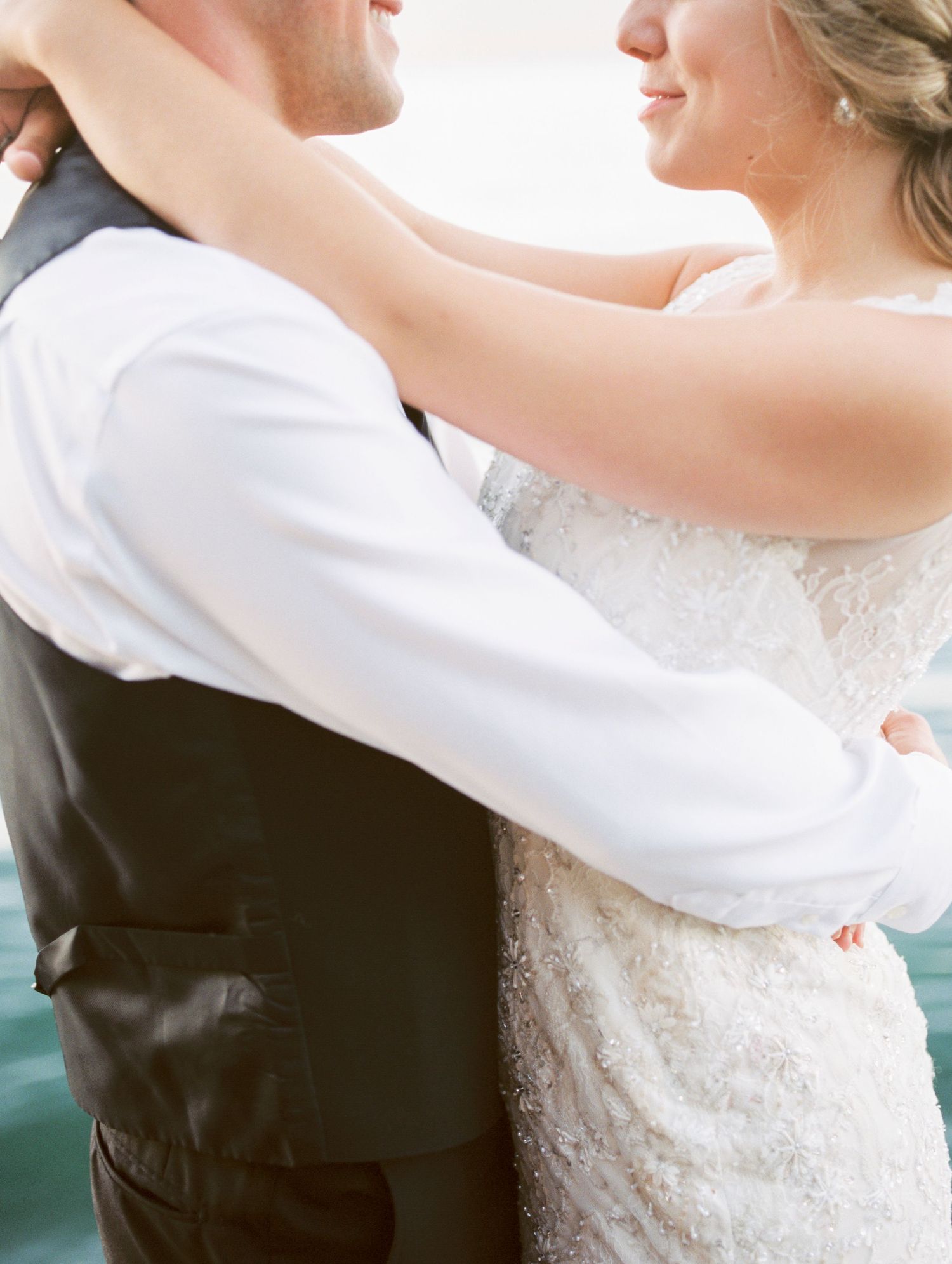 Close-up details of couple dancing together in formal wedding attire.