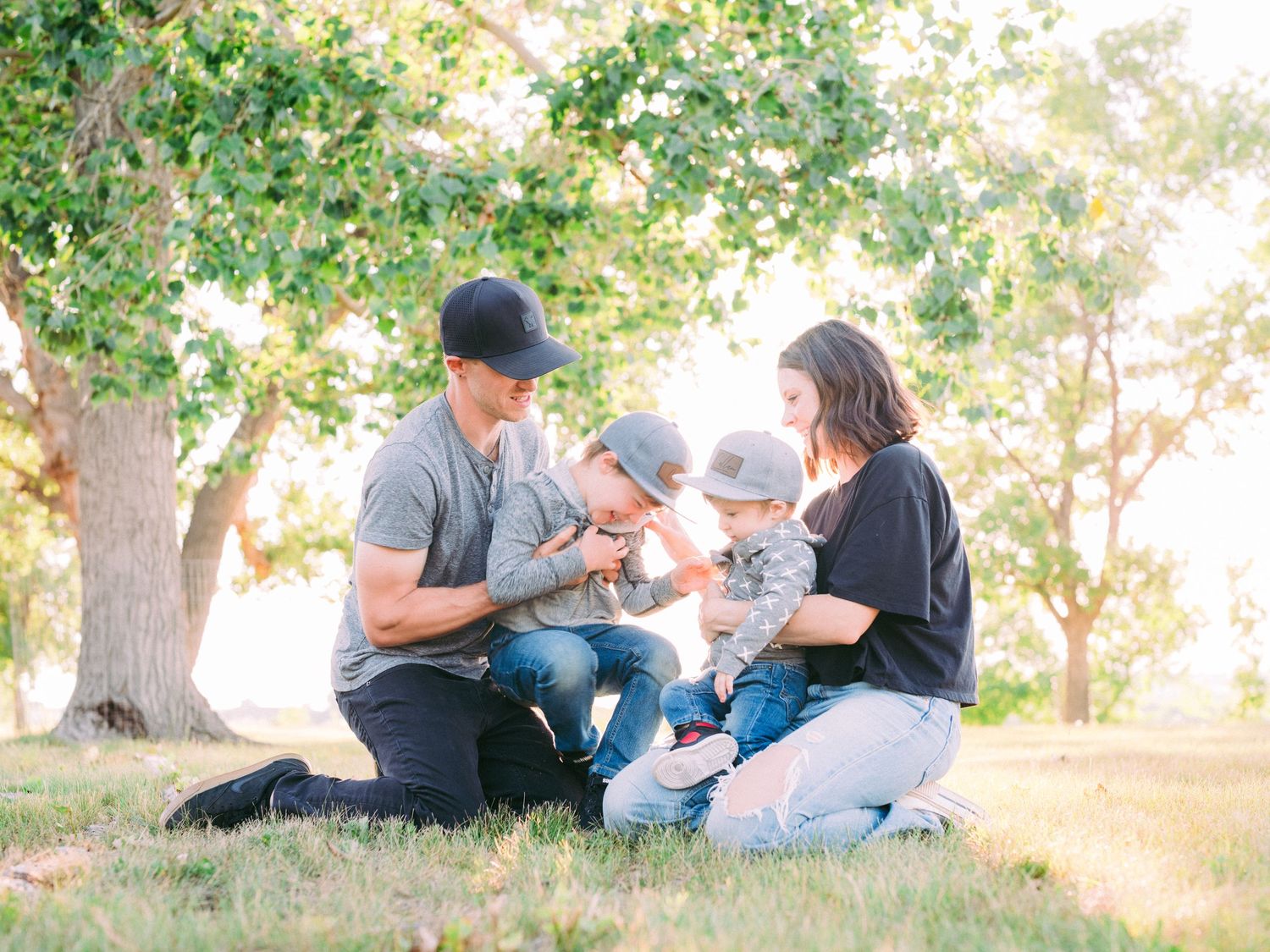 Family relaxing together under shady trees during an outdoor photo session in a park.