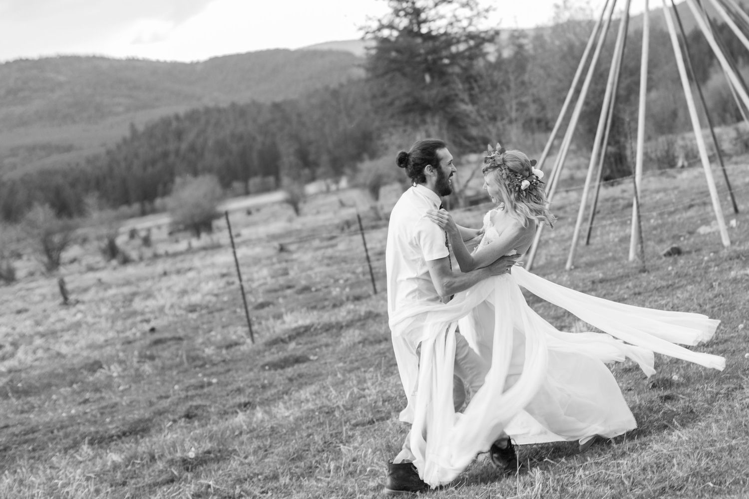 Wedding couple poses together in a scenic mountain landscape with dramatic lighting.