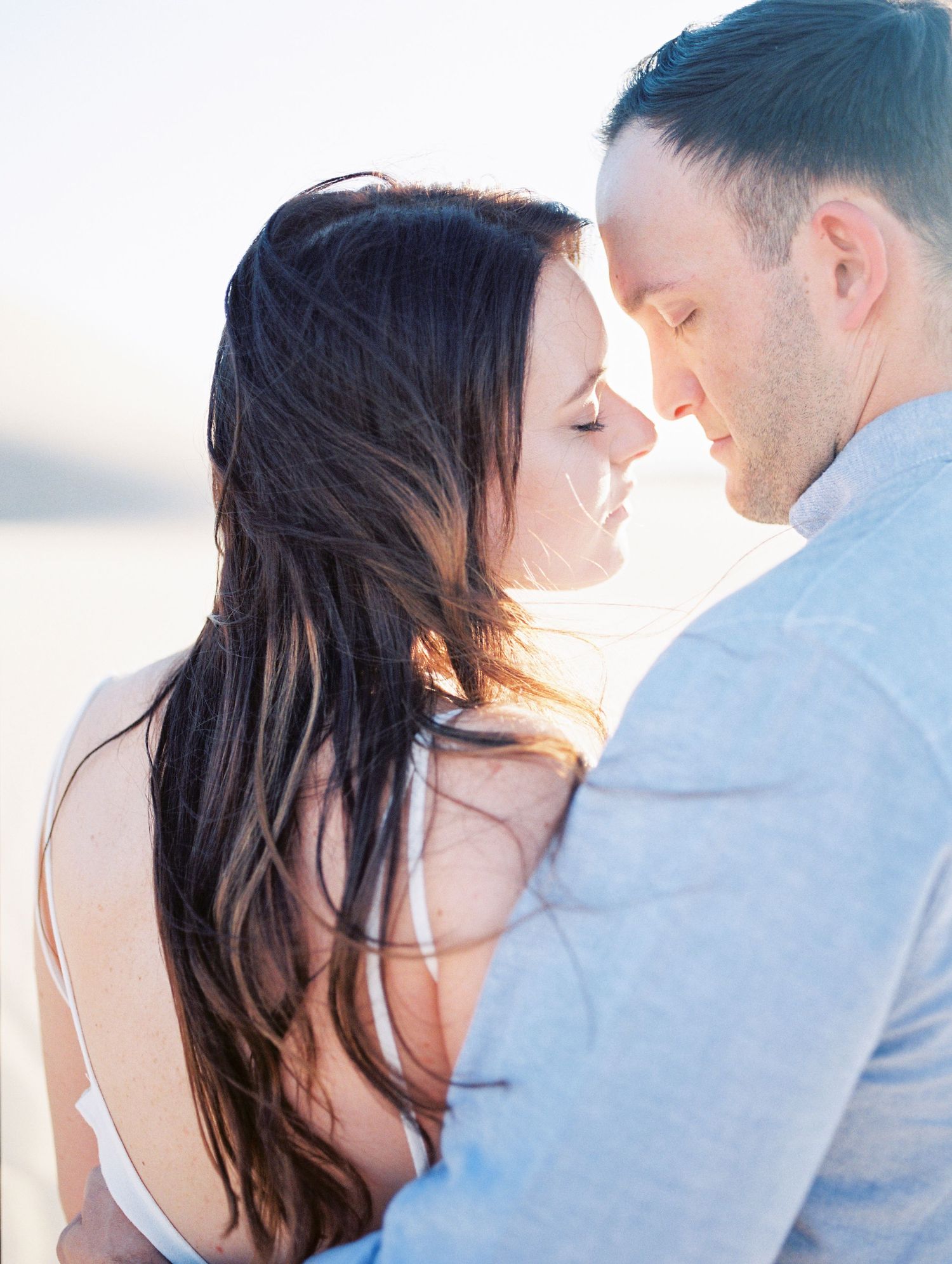 Intimate couple shares tender moment in glowing sunset light.