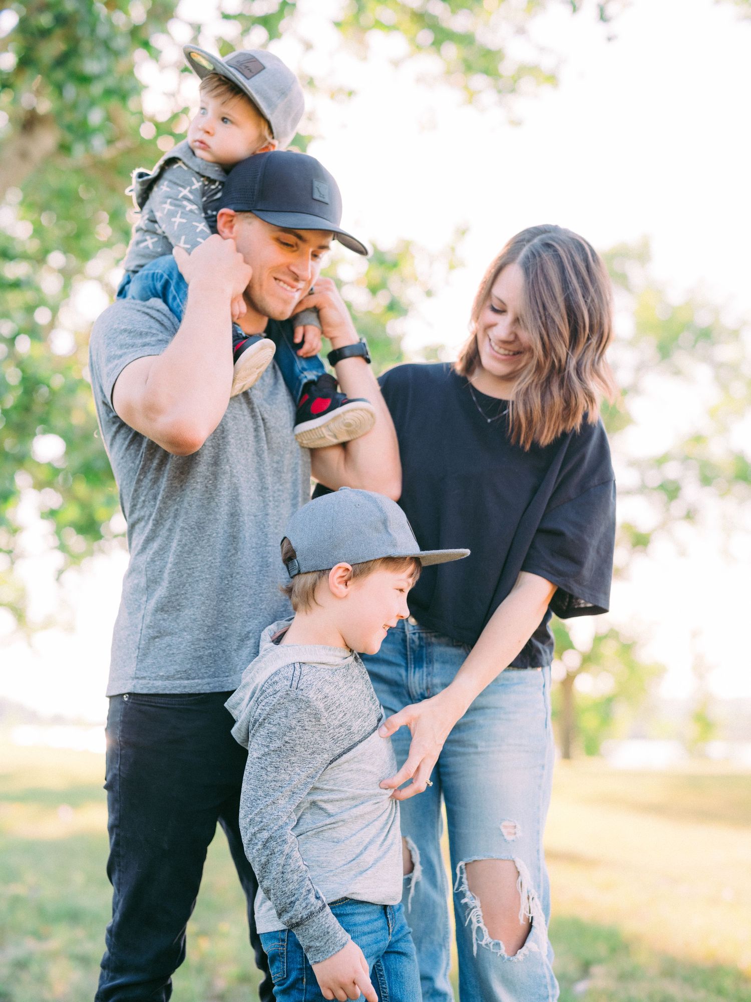 A family shares joyful moments together in a sunny outdoor setting with natural greenery in the background.