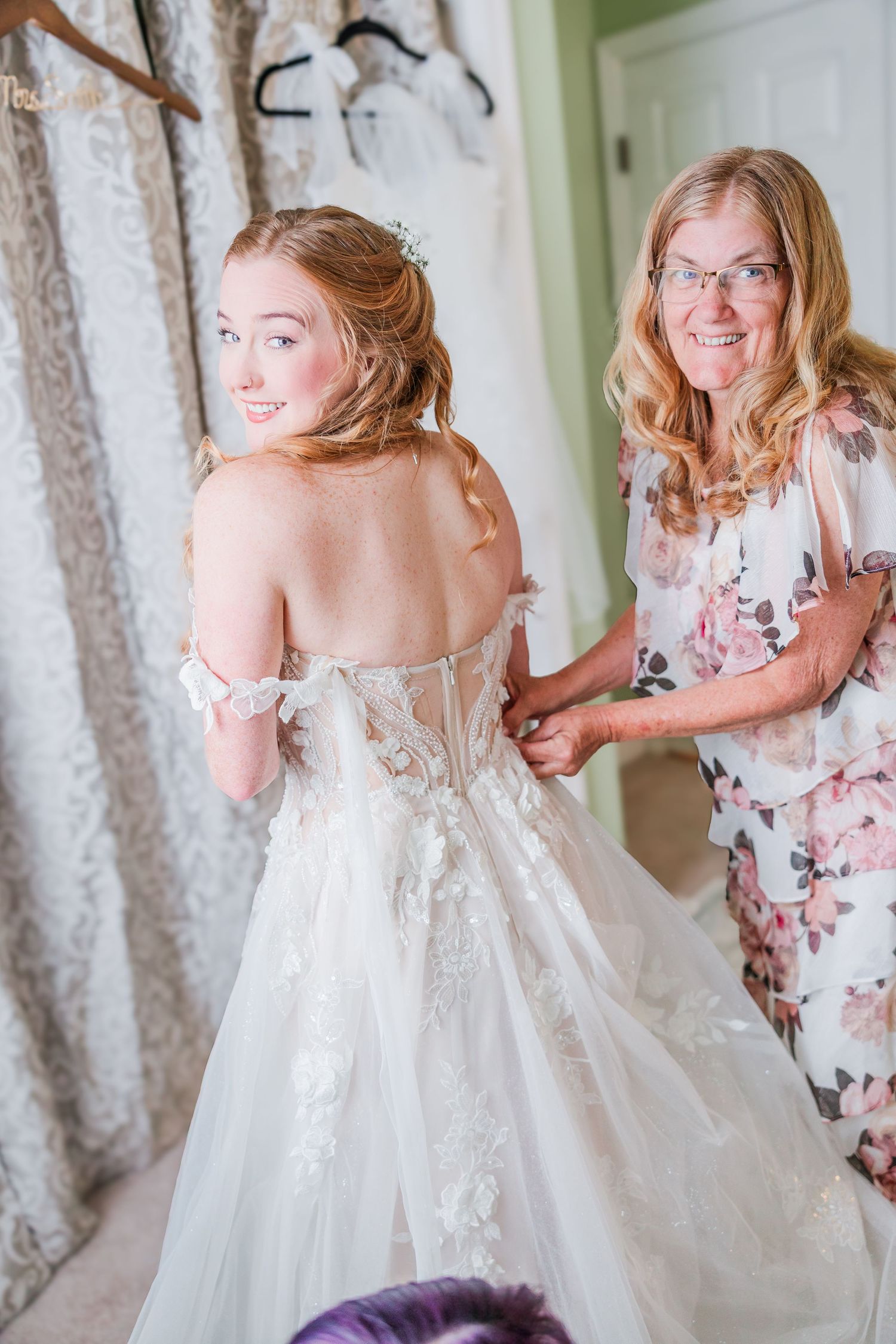 A wedding dress fitting session showing the back details of a white lace gown in a backyard wedding in wilmington, nc