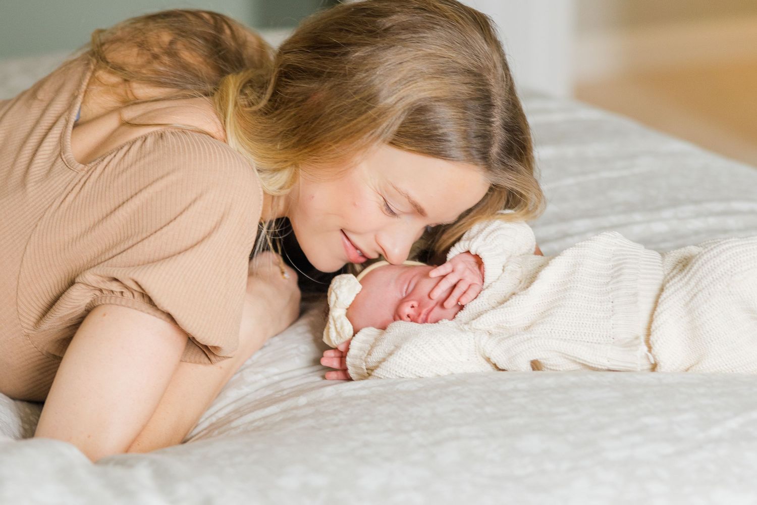 Baby sleeping on white bedding during lifestyle newborn photography session.