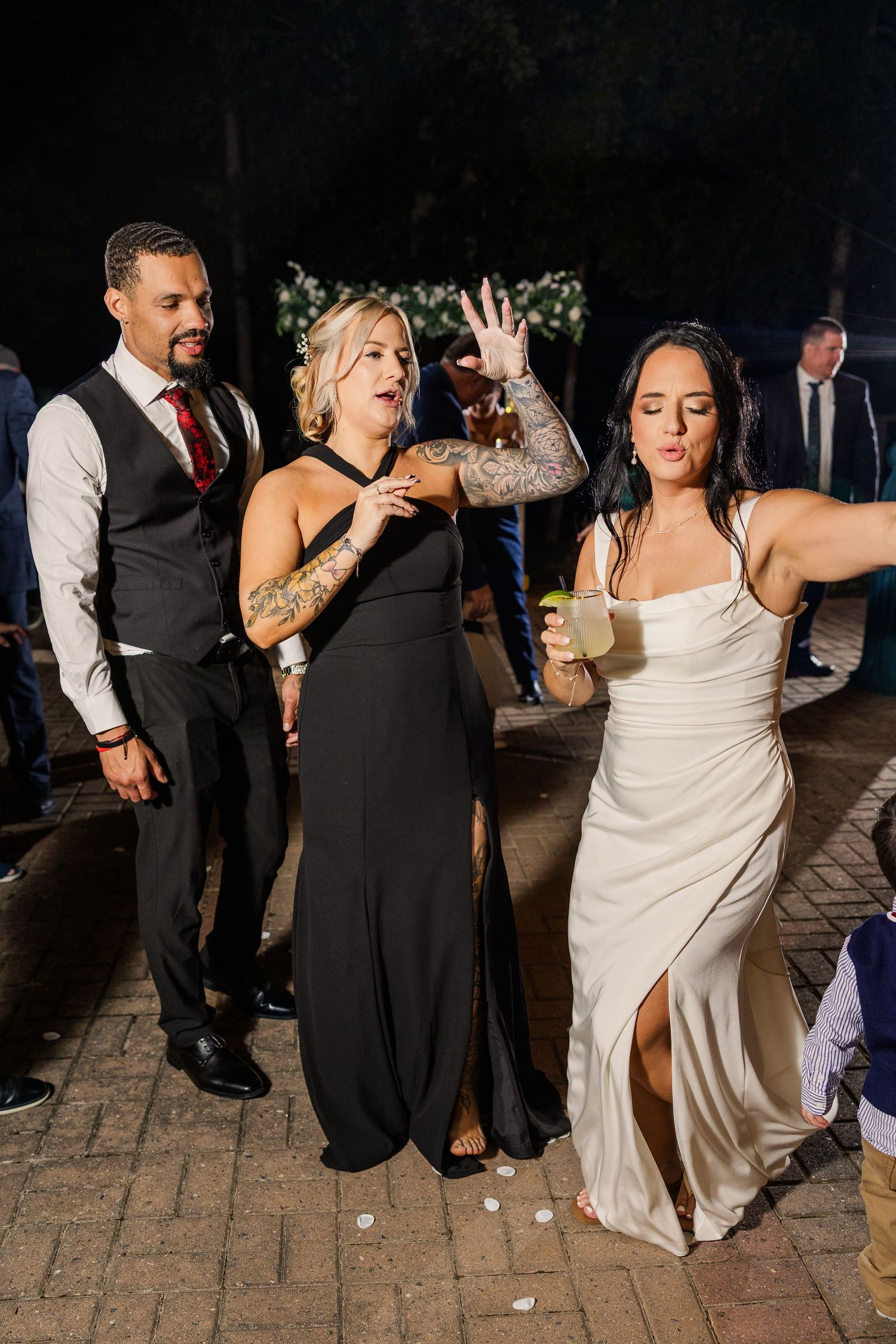 Wedding guests dancing and celebrating on outdoor stone patio at night wedding groom bride lake Gaston photographer light airy