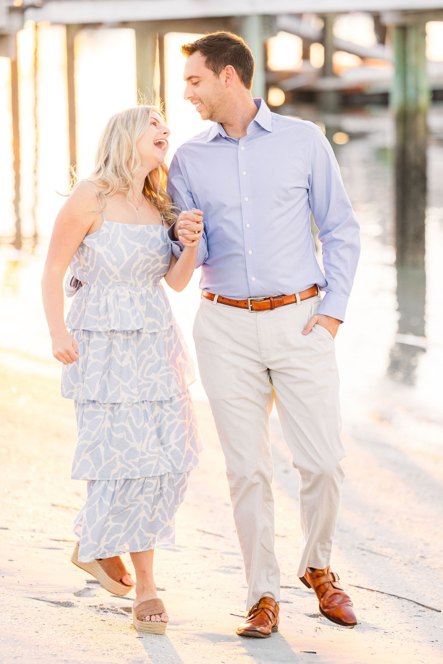 Casual couple strolling along coastal walkway in coordinated blue and white outfits.