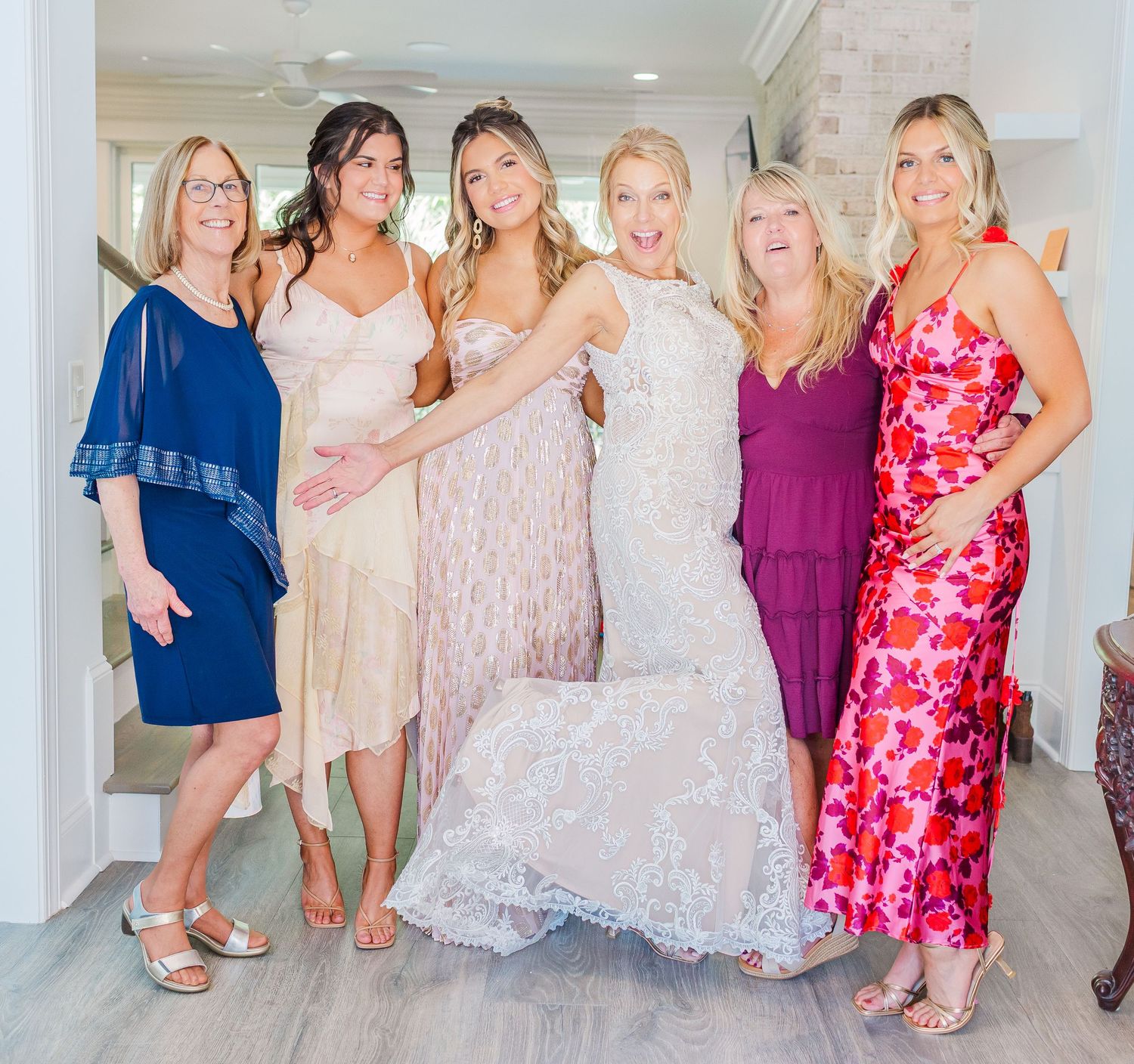 Bridal party poses together in pink, navy, and white dresses.