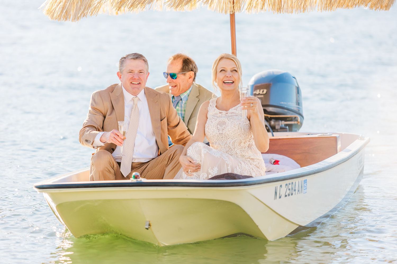 Newlyweds and guests ride in a small white boat during a waterfront celebration.