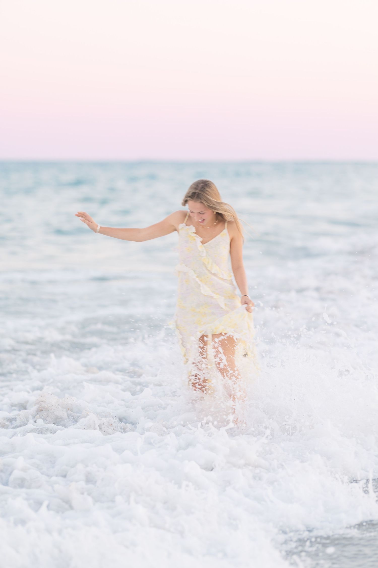 Someone wearing a flowing white dress splashes through ocean waves with ethereal lighting.