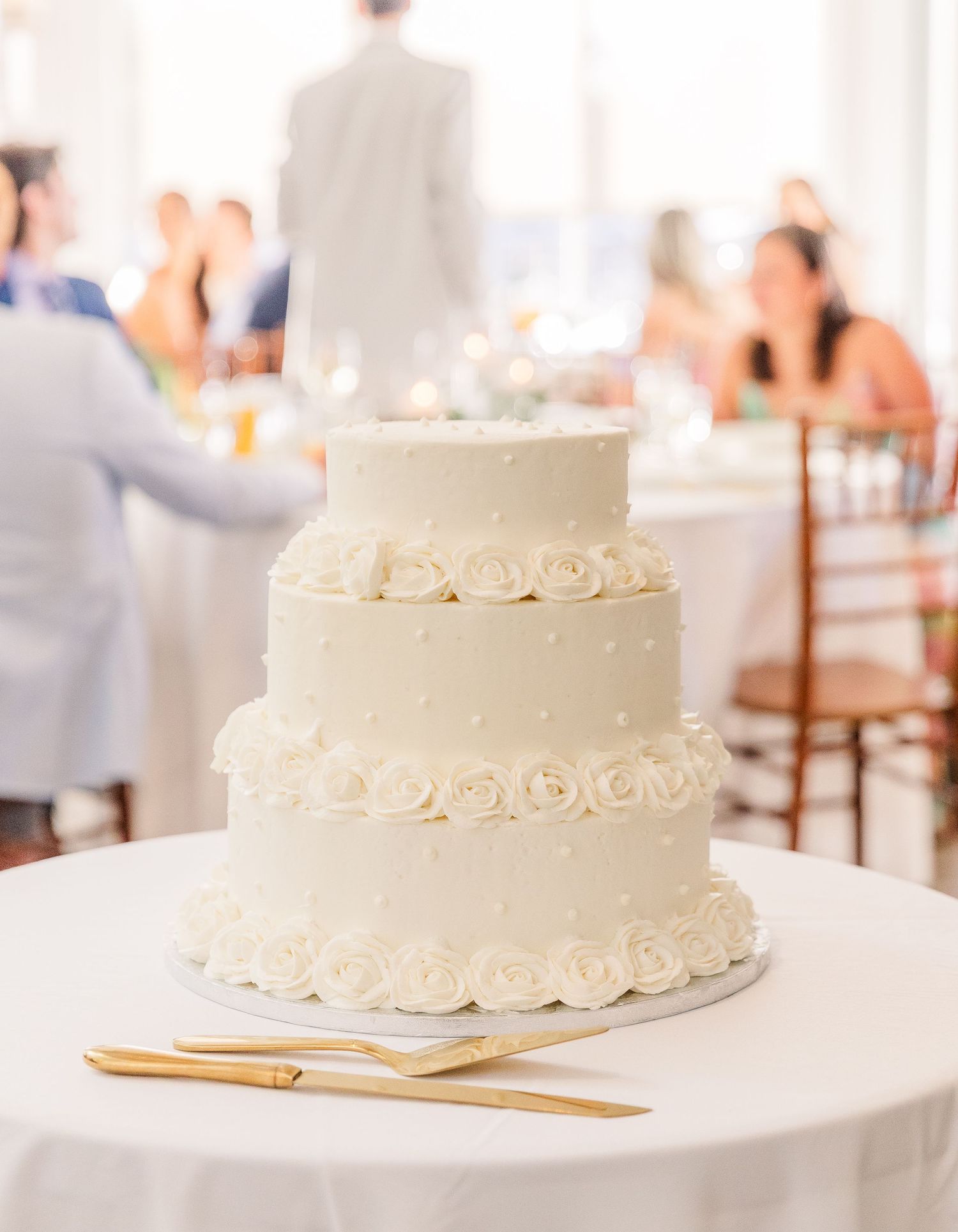 Elegant white wedding cake with simple frosting details displayed on a table.