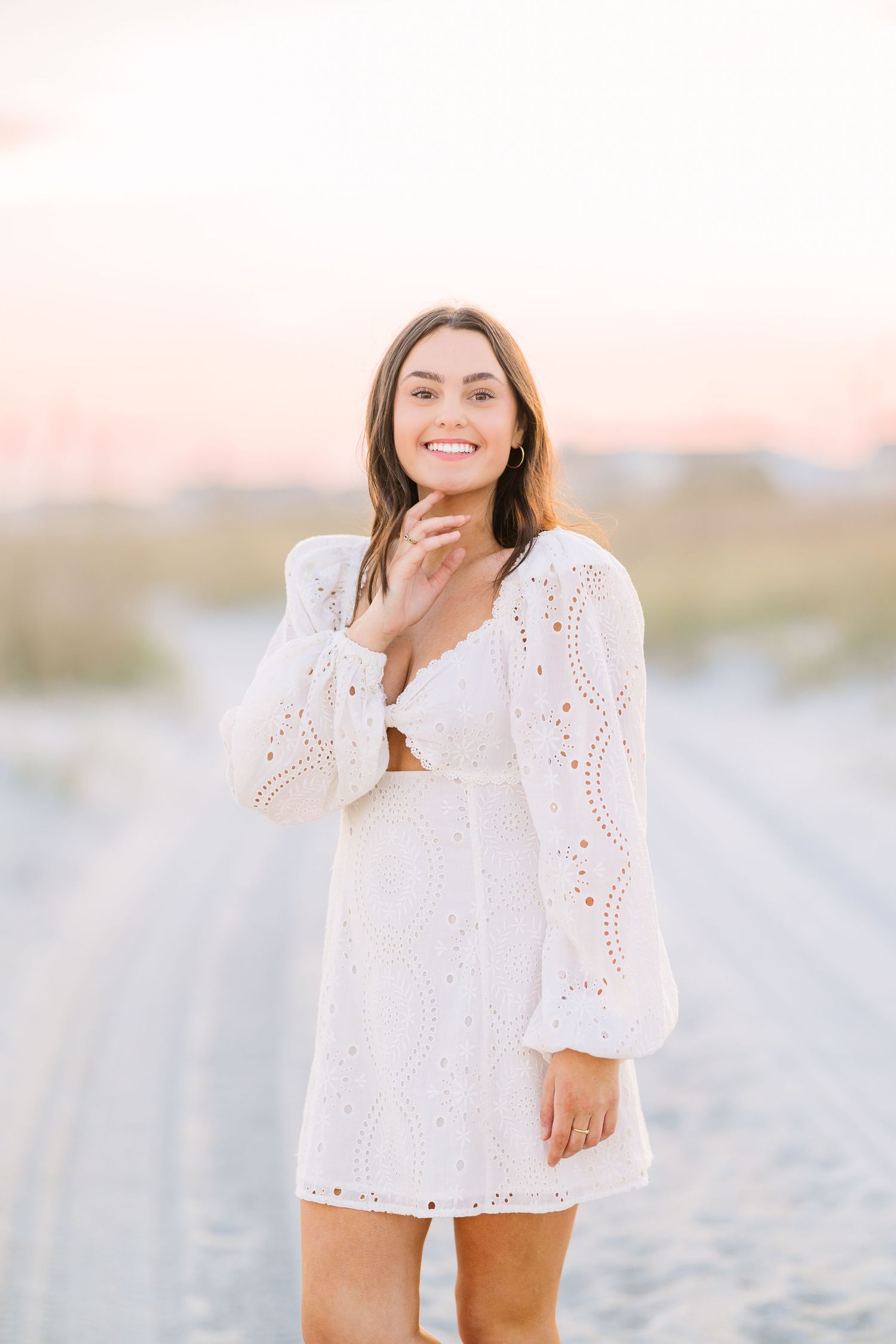 Elegant white summer dress with cutout detail captured in soft sunset lighting at the beach.