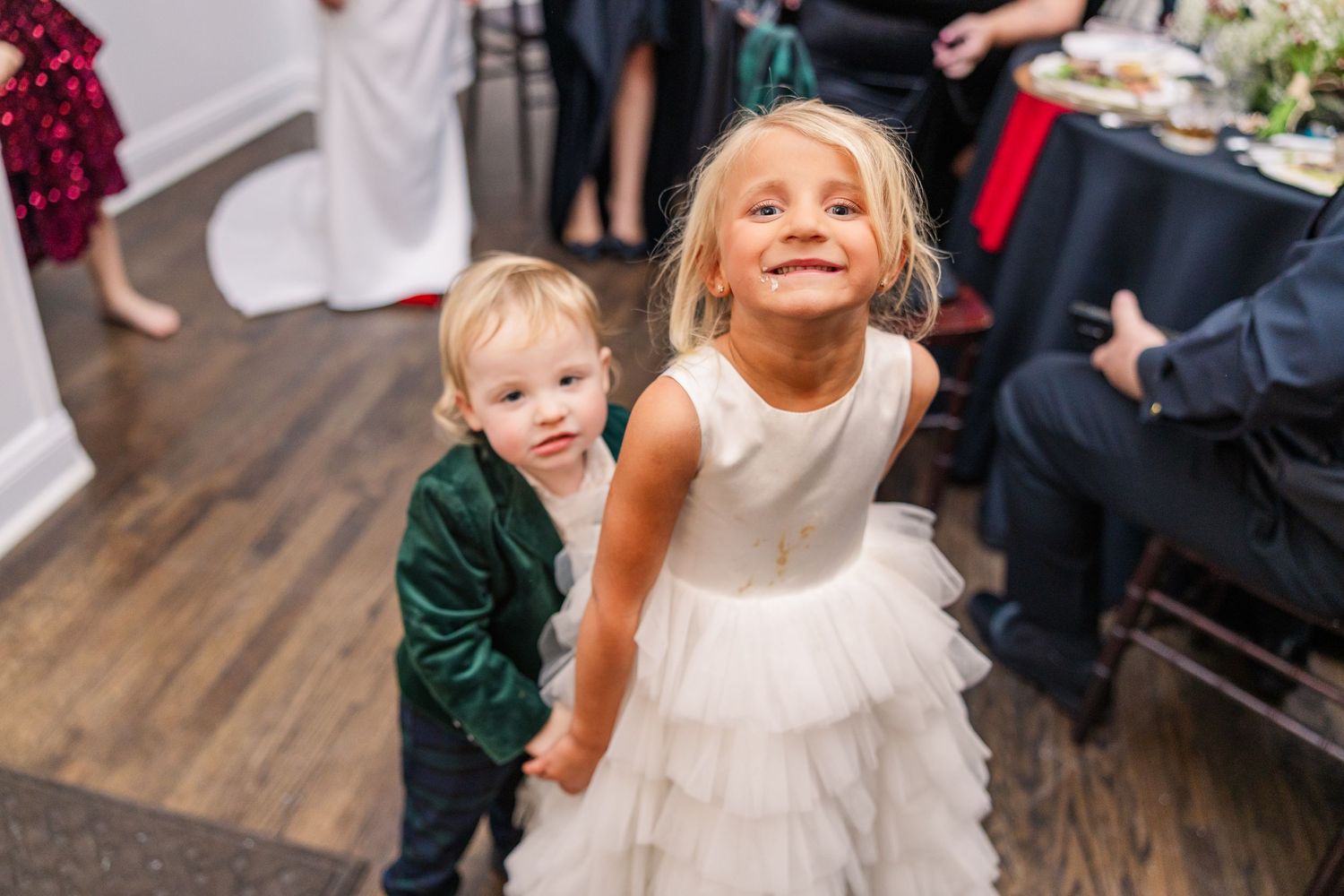 Two young children in formal attire share a playful moment on a wooden dance floor at a wedding reception wedding groom bride wilmington