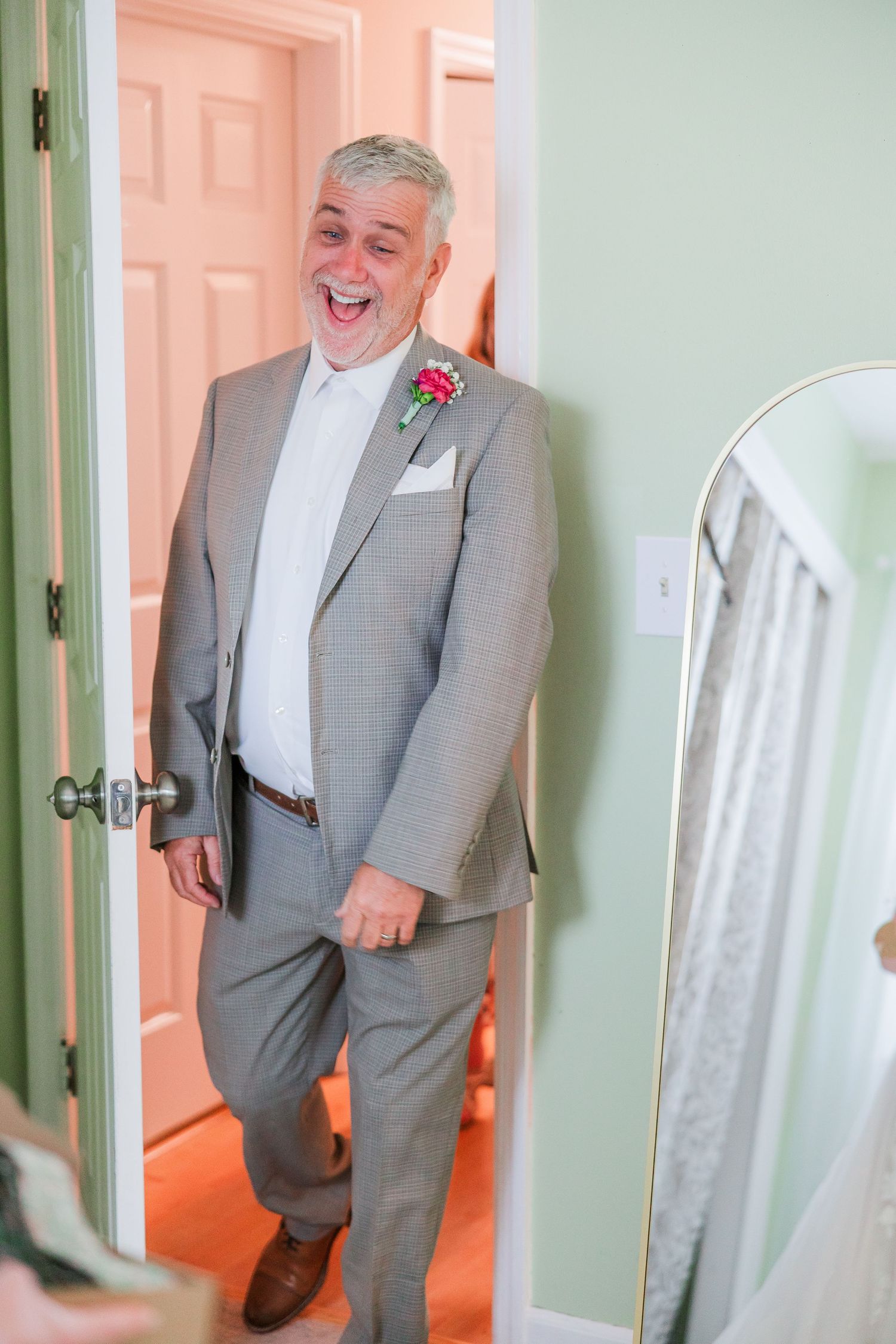 A joyful reaction during a wedding first look moment in a mint green room in a backyard wedding in wilmington, nc