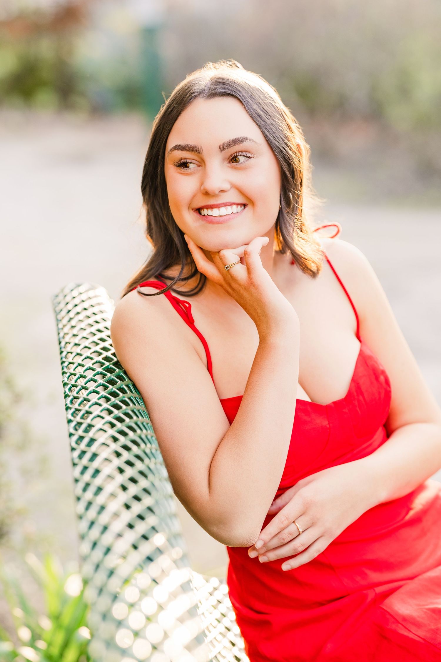 Casual outdoor portrait on green bench with natural lighting and garden scenery.