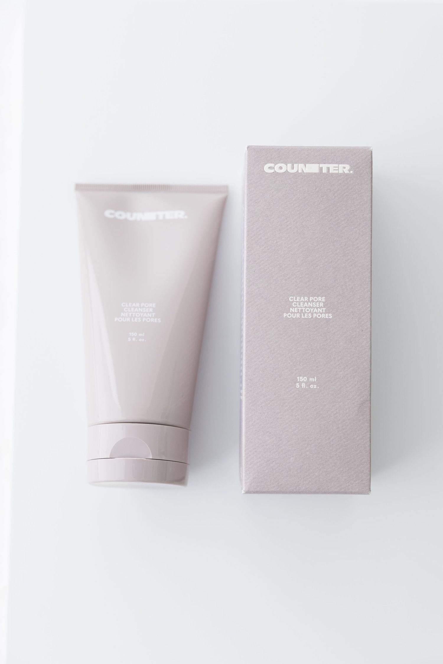 Minimalist skincare product packaging in soft pink and gray tones displayed against white background.