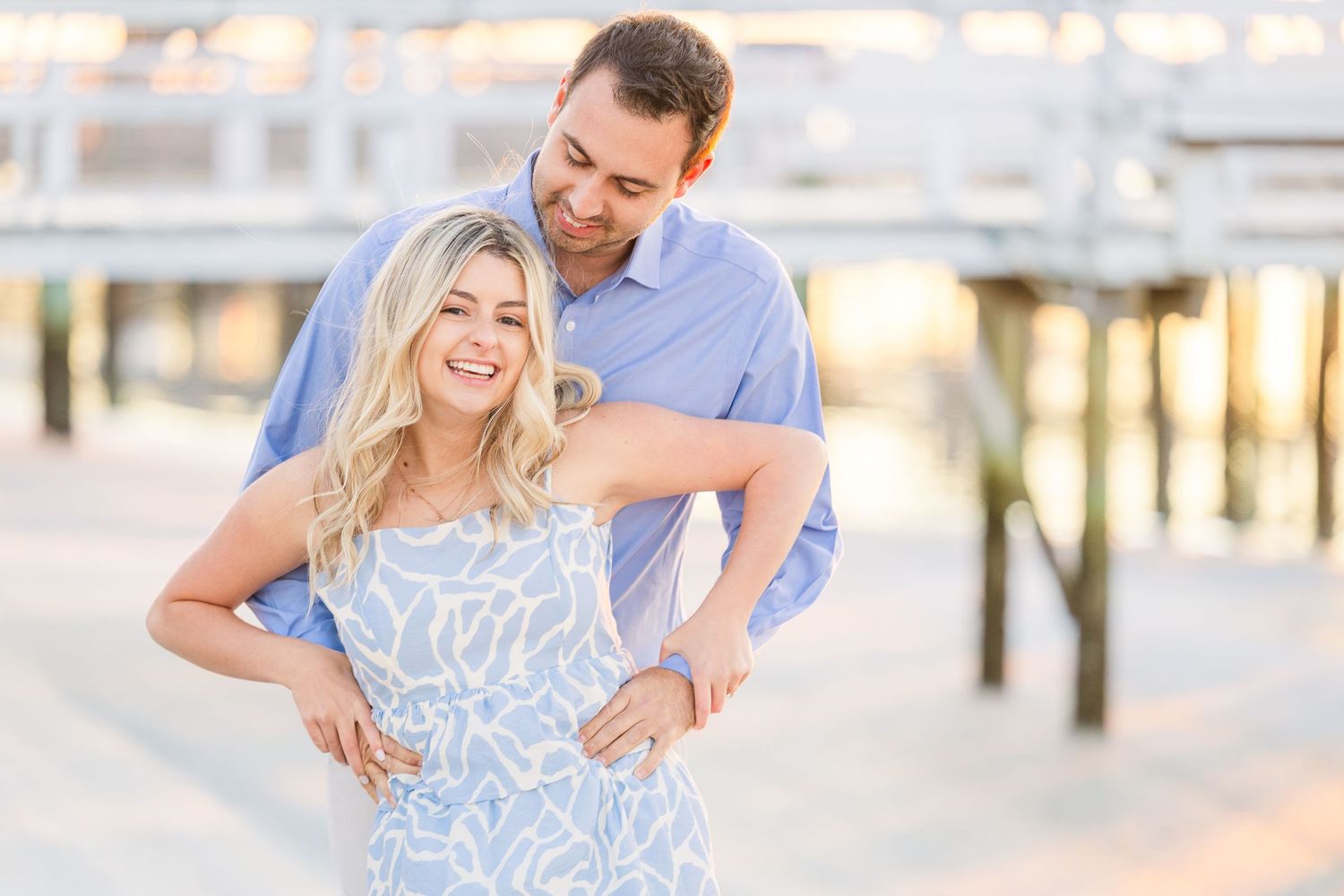 A romantic engagement photo session at sunset with a couple in light blue and white outfits.