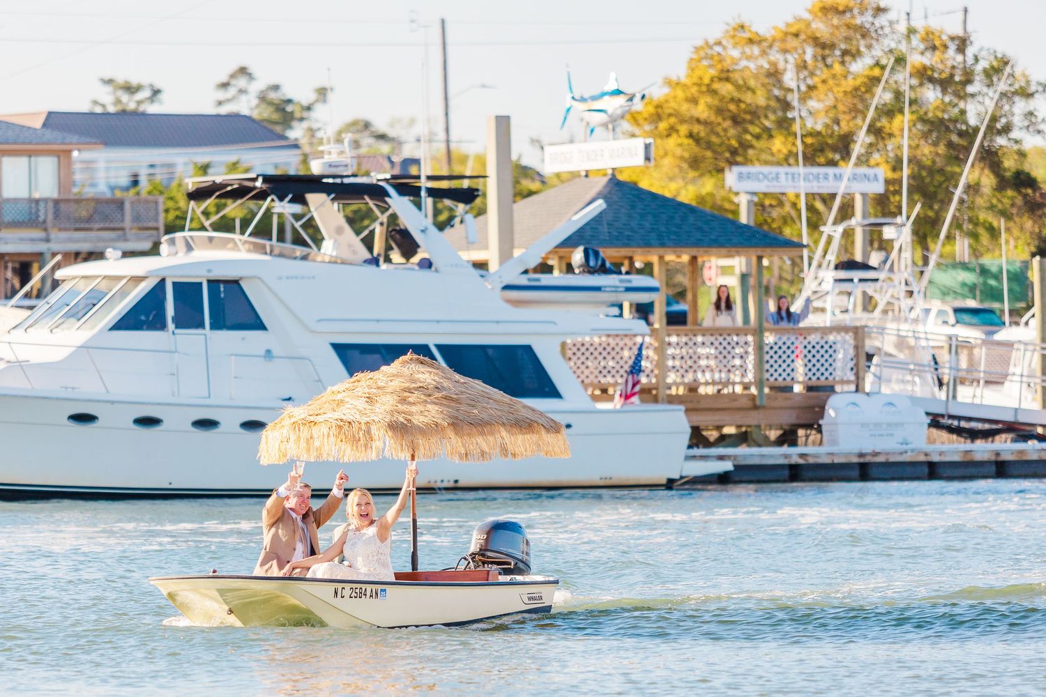 Multiple boats anchored in a marina with thatched umbrellas visible on a sunny day.