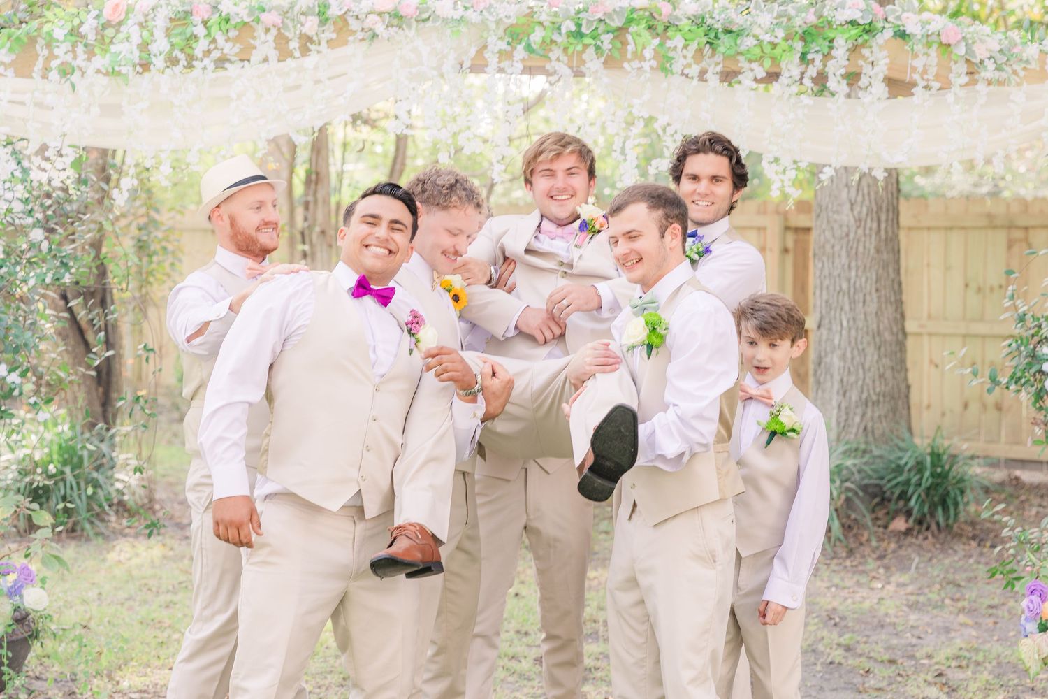 Groomsmen in light colored suits pose playfully for outdoor wedding photos wedding groom bride wilmington photographer light and airy