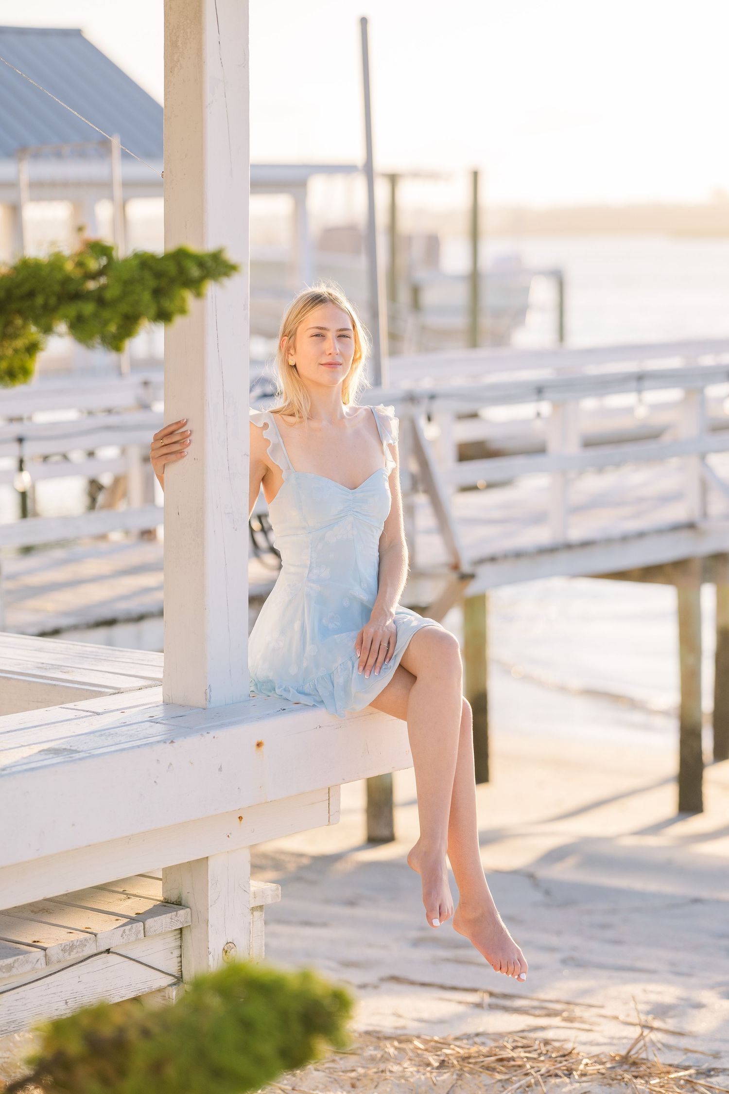 Serene coastal dock scene with white benches and golden afternoon light.