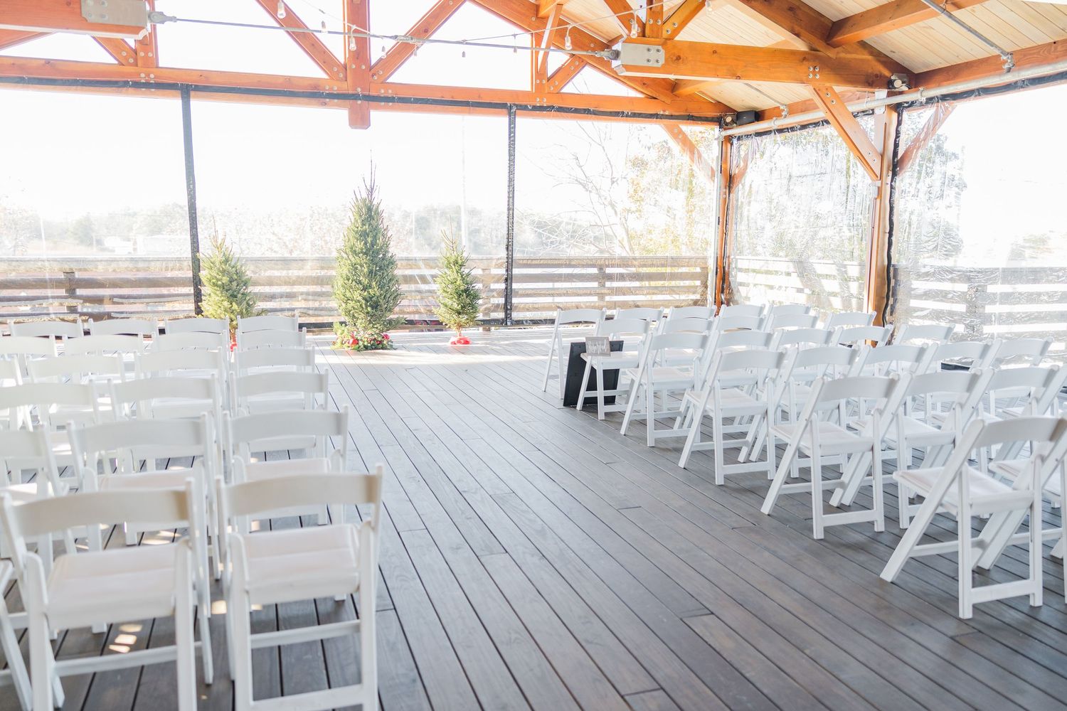 A covered outdoor wedding venue with rows of white chairs set up for a ceremony.