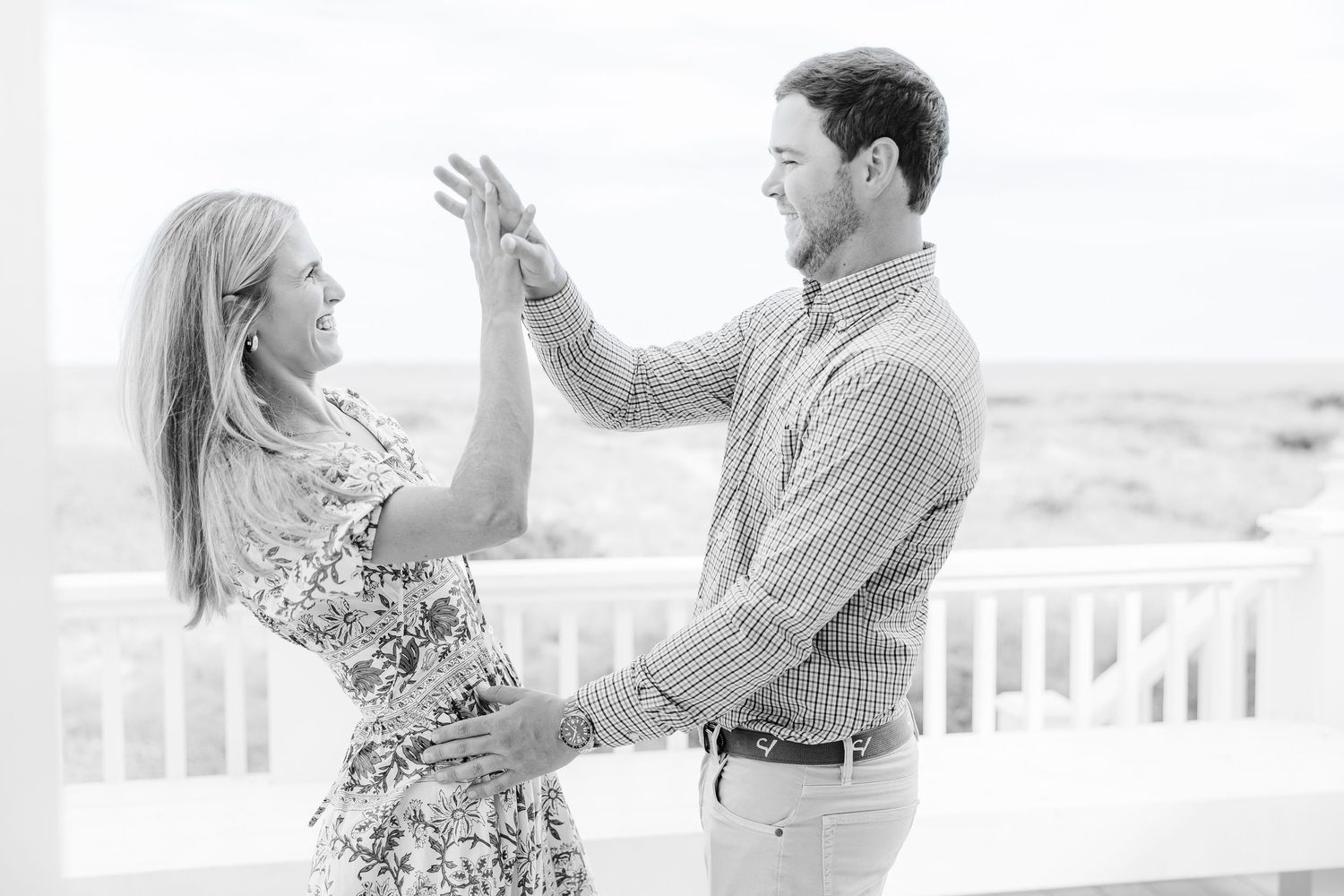 A couple shares a romantic moment on a sun-lit beach deck.