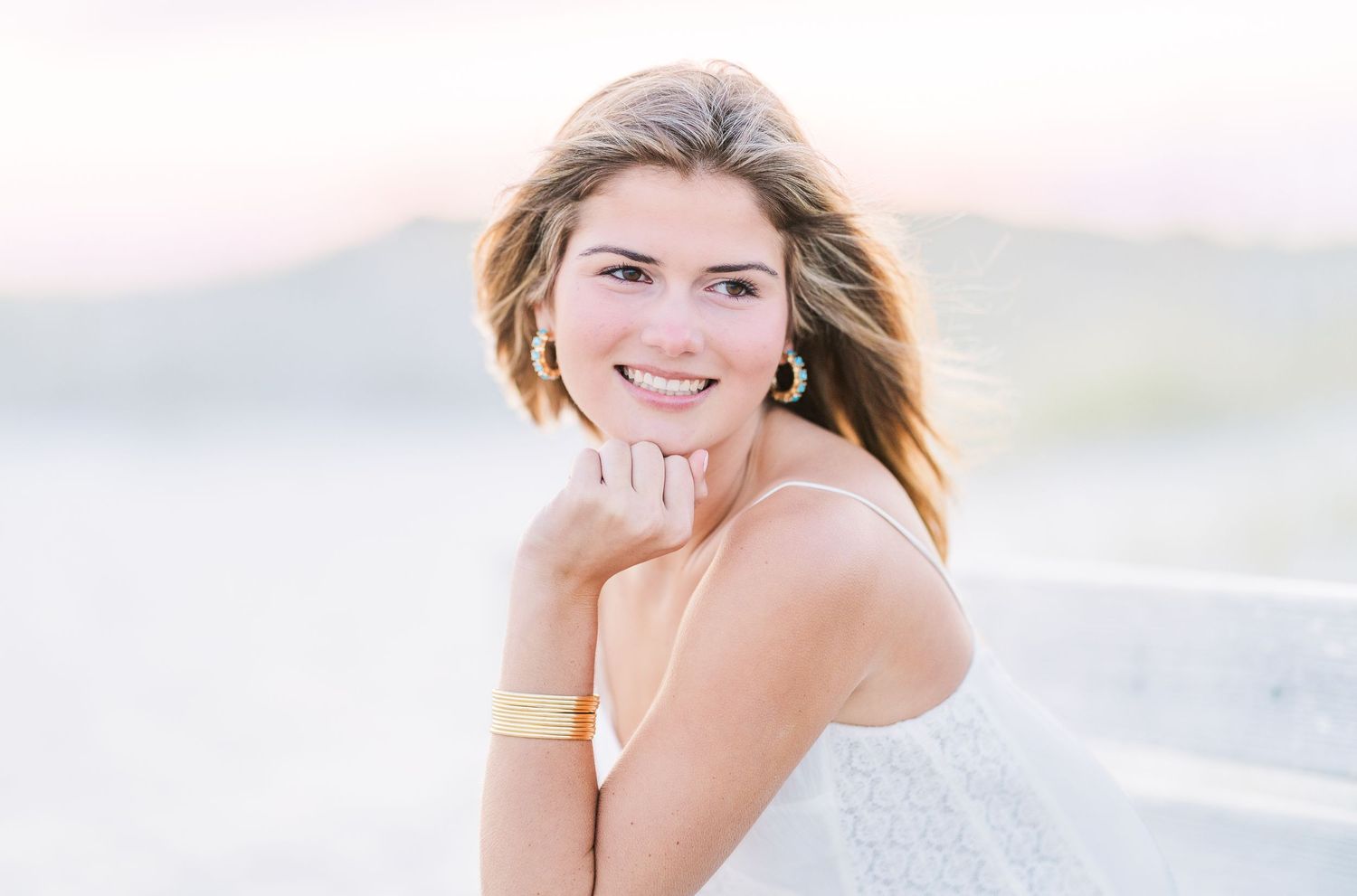 Coastal portrait session featuring flowing white fabric and soft sunset lighting.