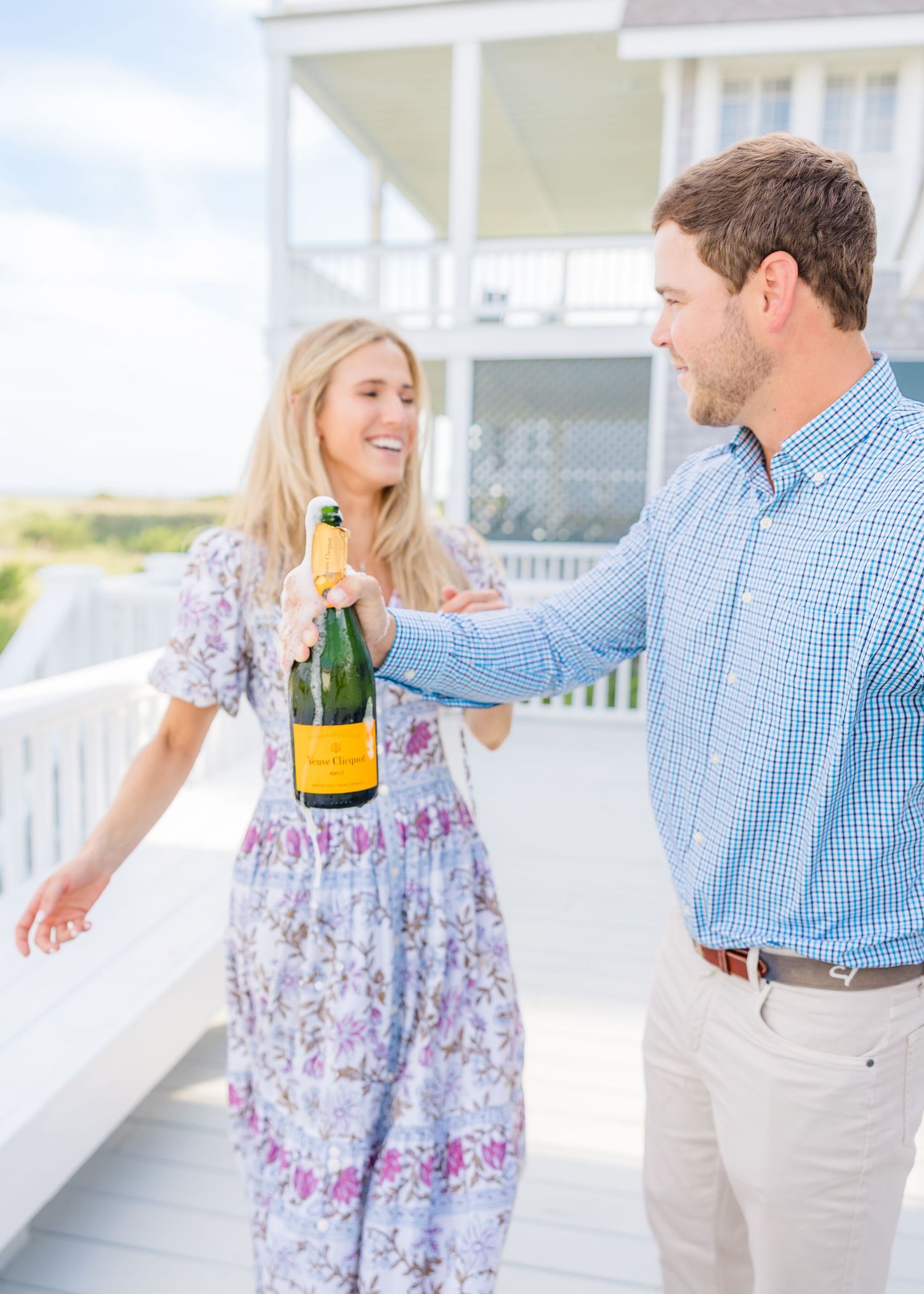 A celebratory moment unfolds on a bright coastal porch with champagne.