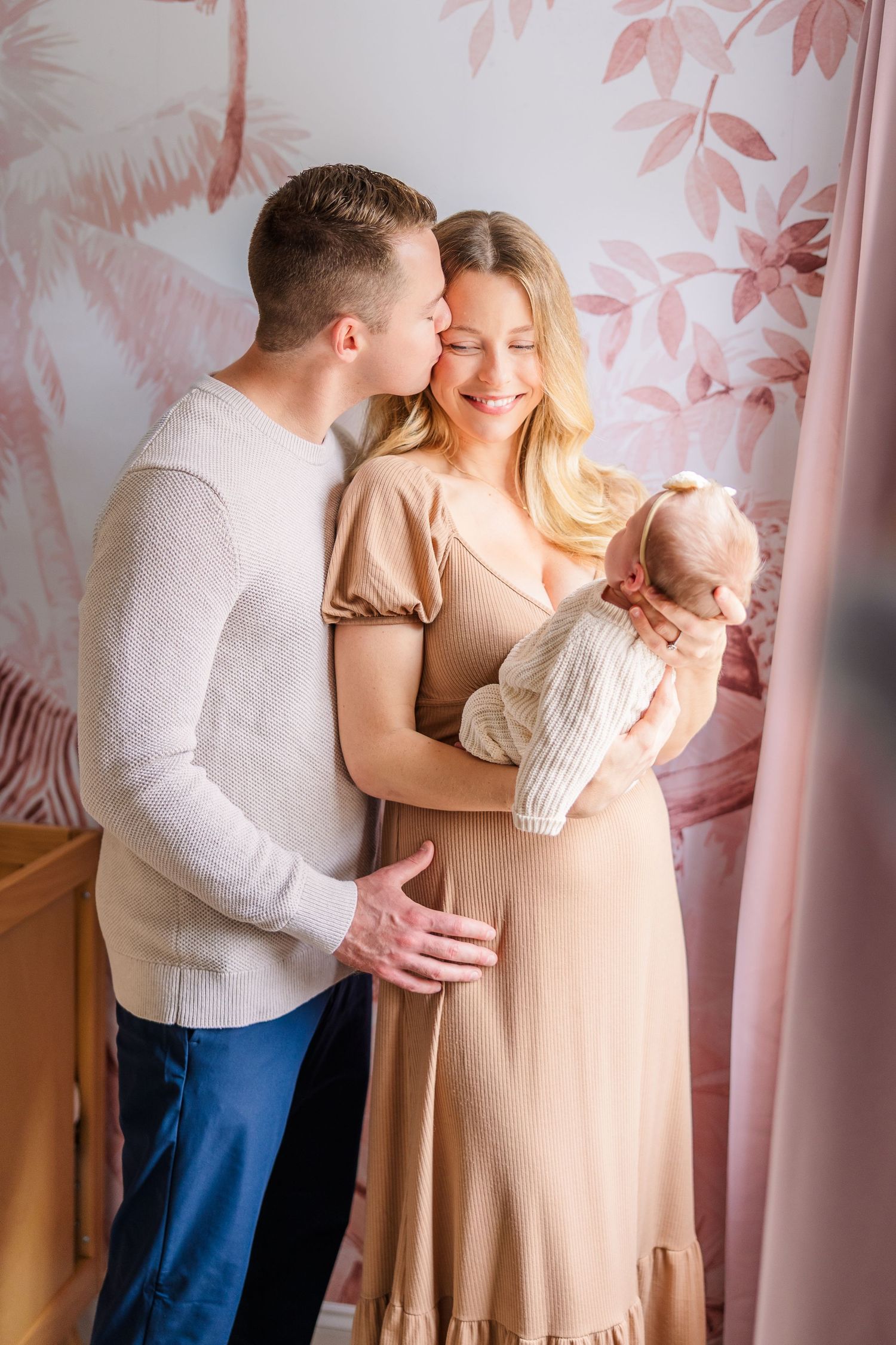 Intimate family photos captured in a room with pink floral accent wall.