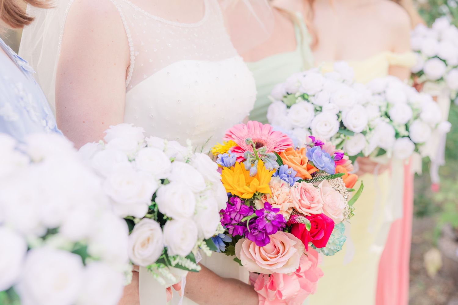 Close-up of colorful and white wedding bouquets held against white dresses wedding groom bride wilmington photographer light and airy classi