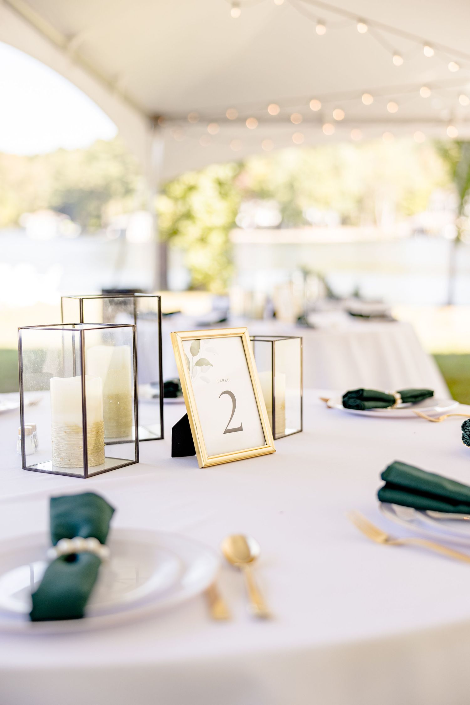 Elegant table settings with gold frames and dark green napkins at a formal event under string lights wedding groom bride lake Gaston photogr