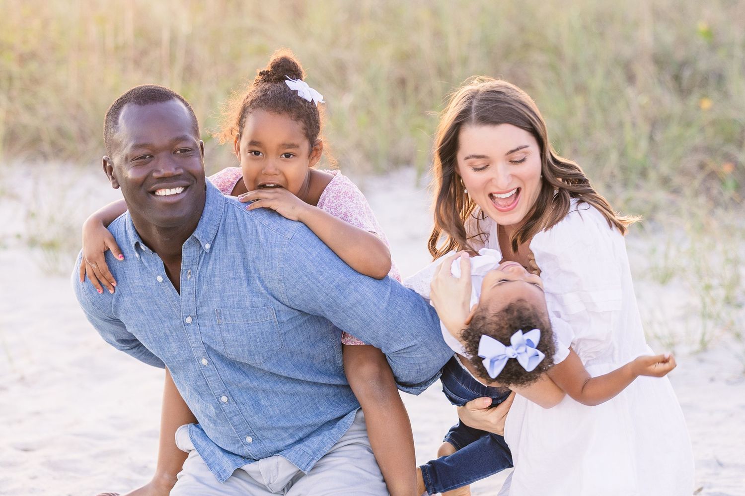 Playful family portrait on the beach with everyone laughing.