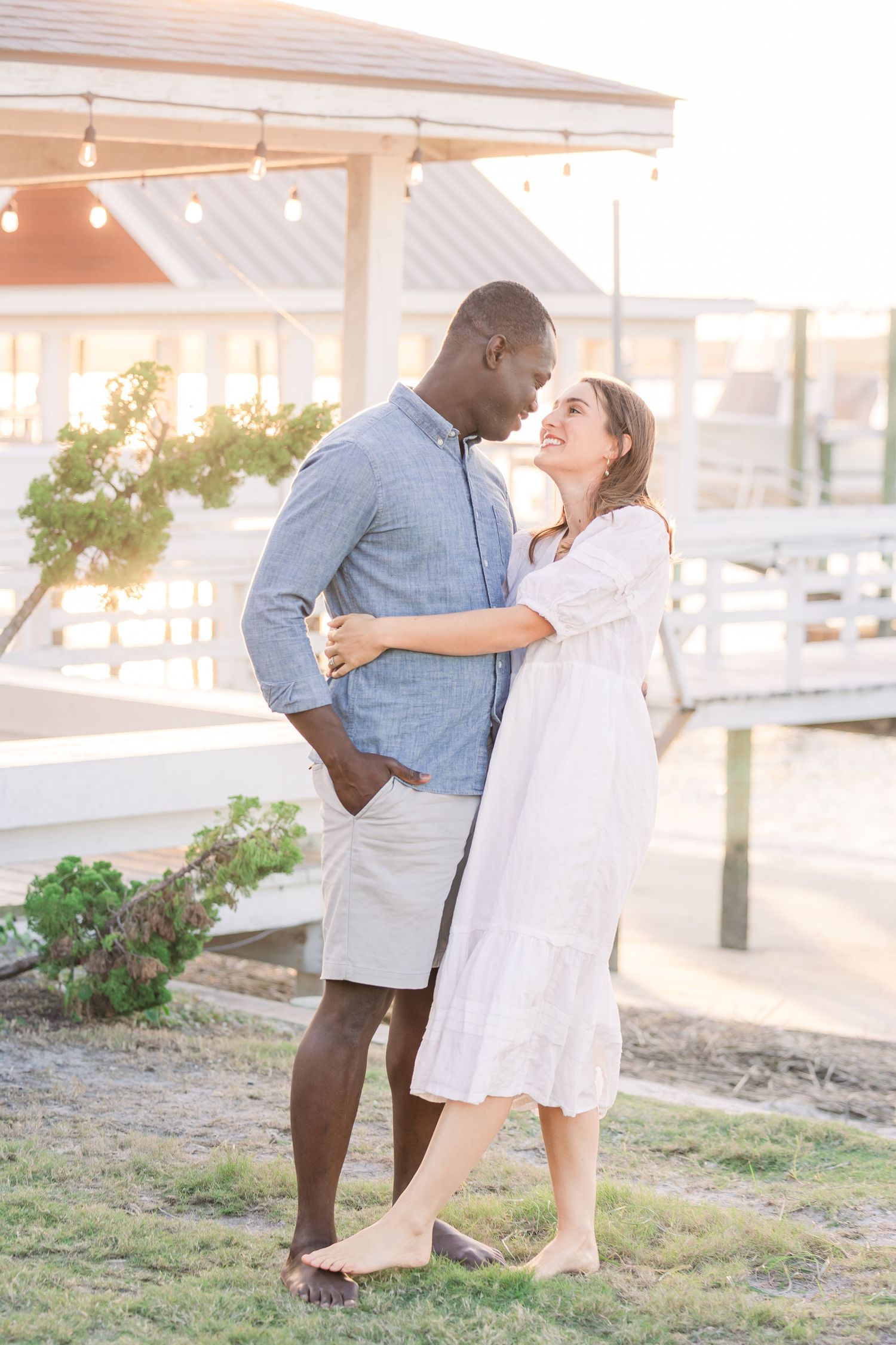 Couple shares intimate moments on a sunlit coastal pathway.
