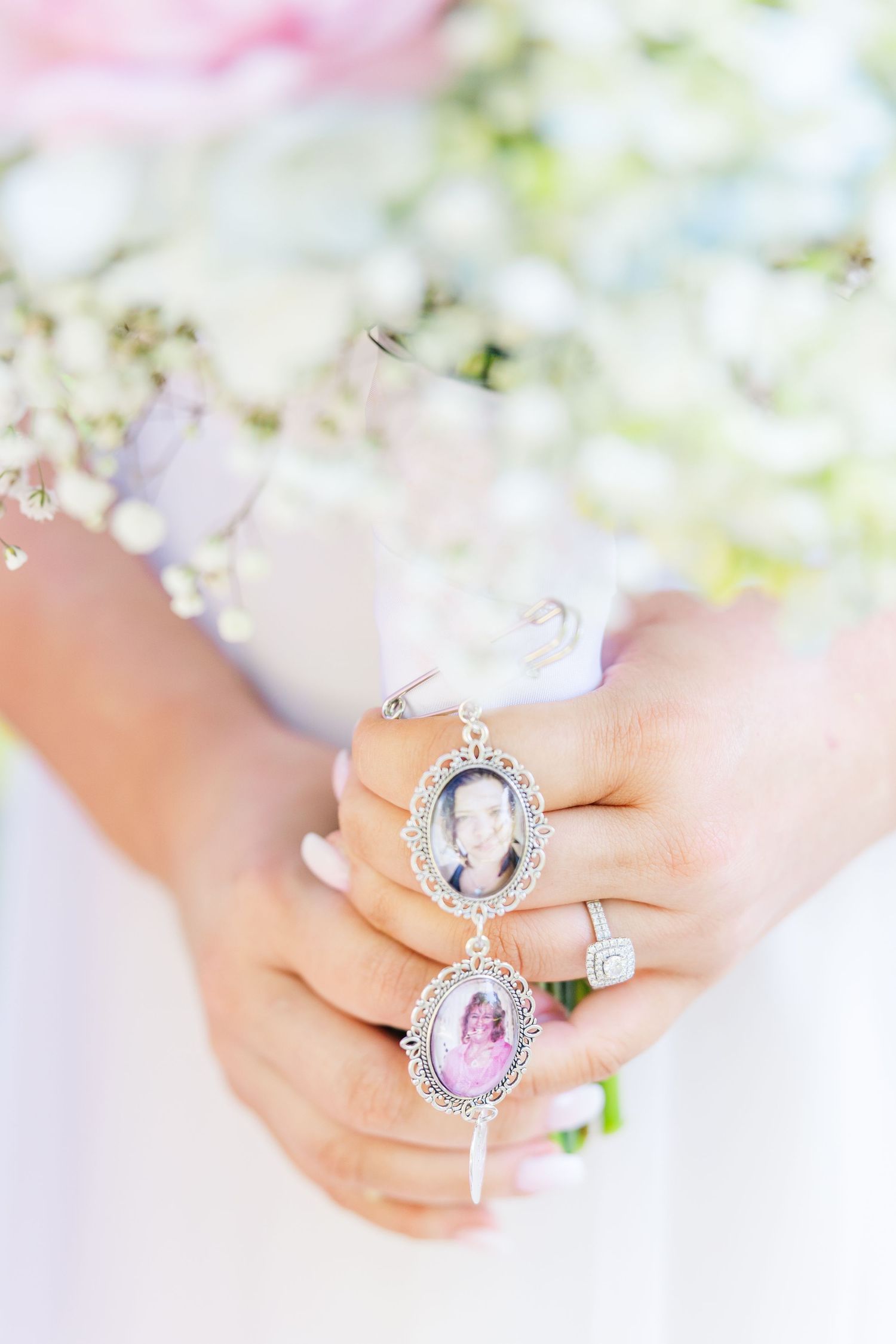 Bride holds bouquet charm locket with memorial photos and diamond engagement ring at wedding in Airlie Gardens in Wilmington, NC