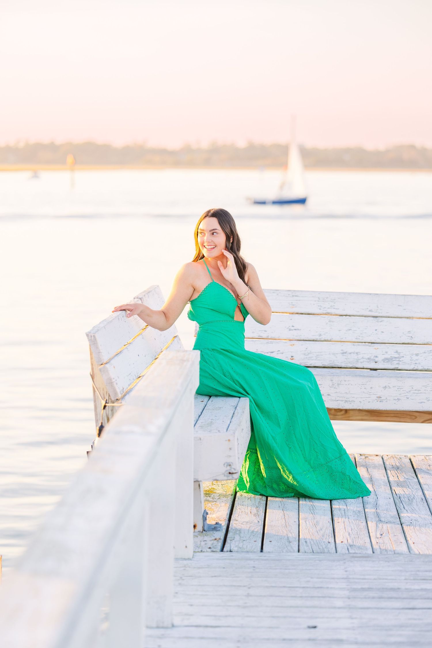 A bright green dress provides contrast against a white coastal dock during golden hour.
