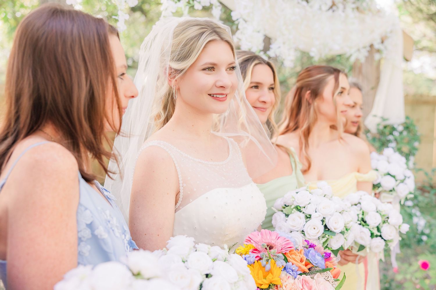 Line of bridesmaids holding mixed floral bouquets at outdoor wedding ceremony wedding groom bride wilmington photographer light and airy