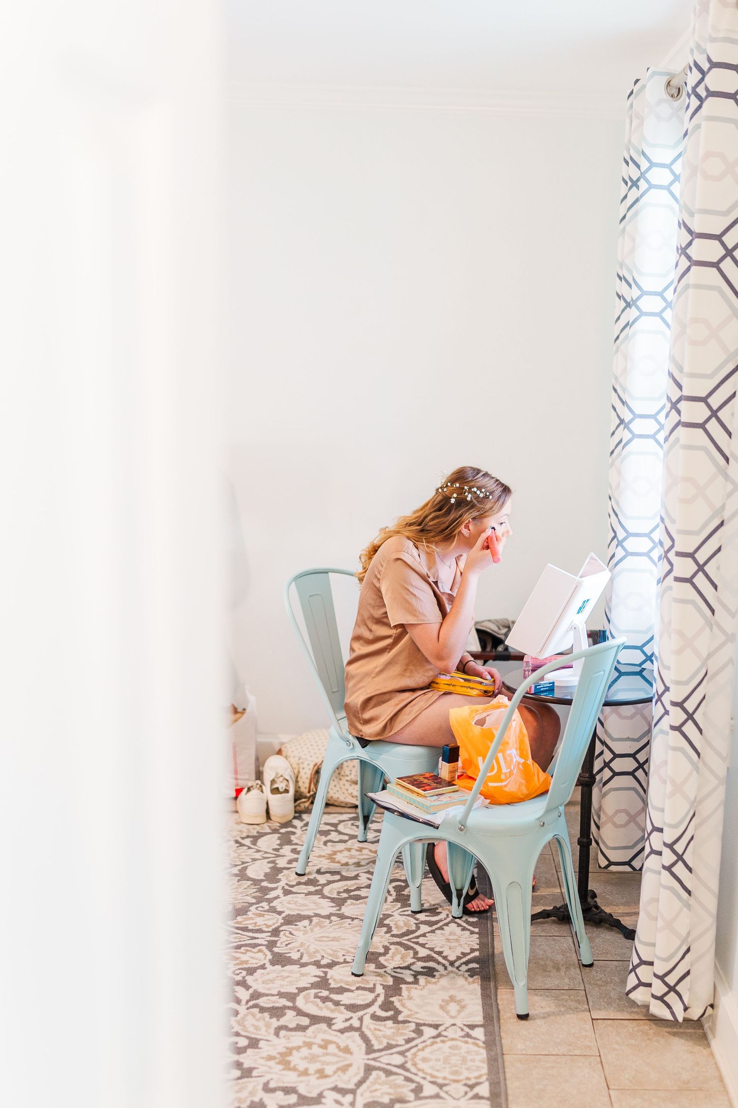 Woman in casual clothing sitting in turquoise chair looking at phone southport elopement wedding bride groom light and airy classic