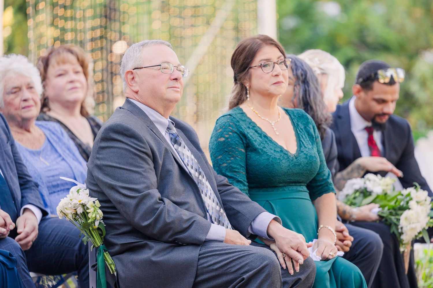 Wedding guests seated outdoors watching ceremony in front of colonial style building wedding groom bride lake Gaston photographer light airy