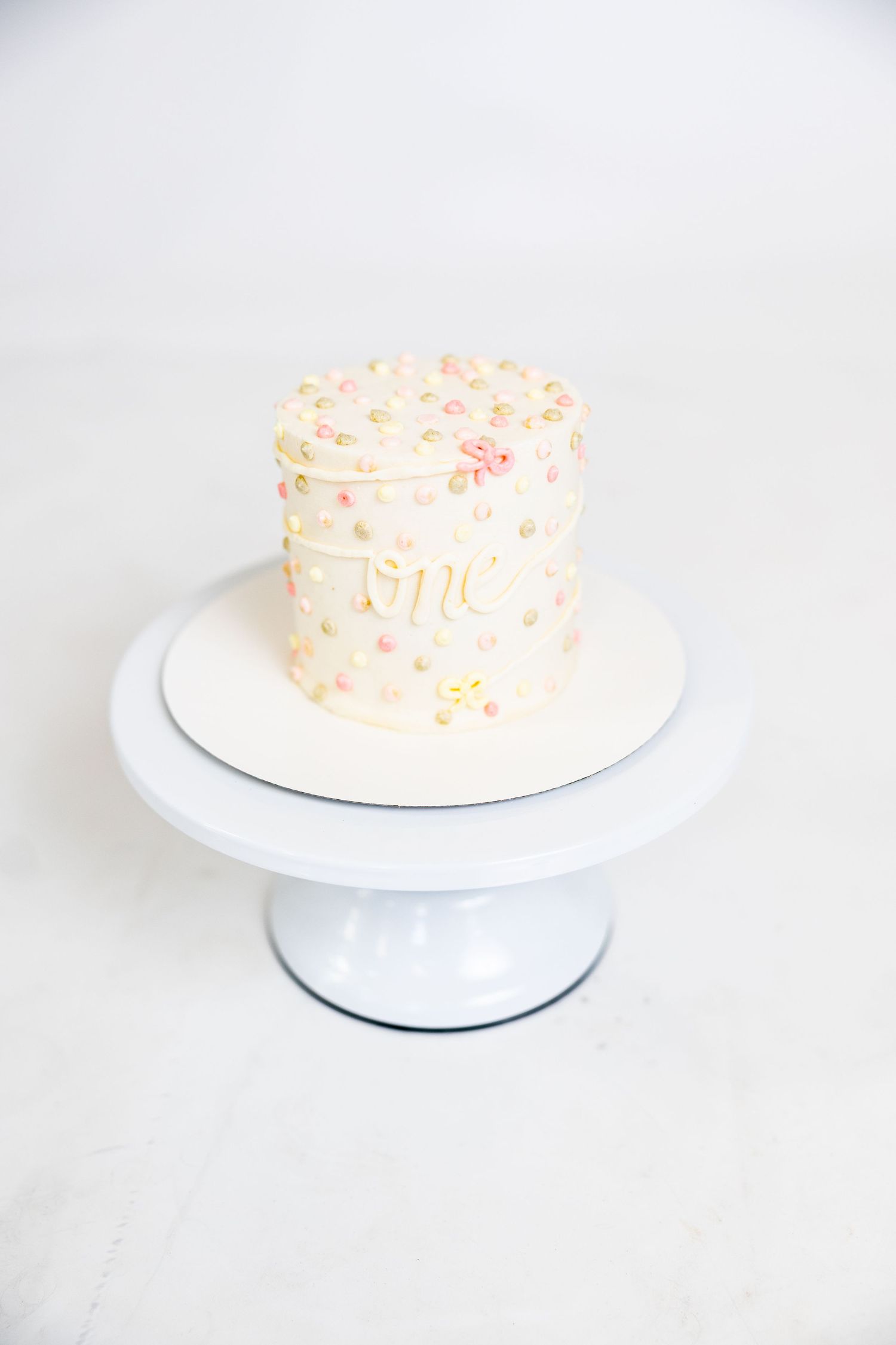 White cake with pink sprinkles displayed on white cake stand.