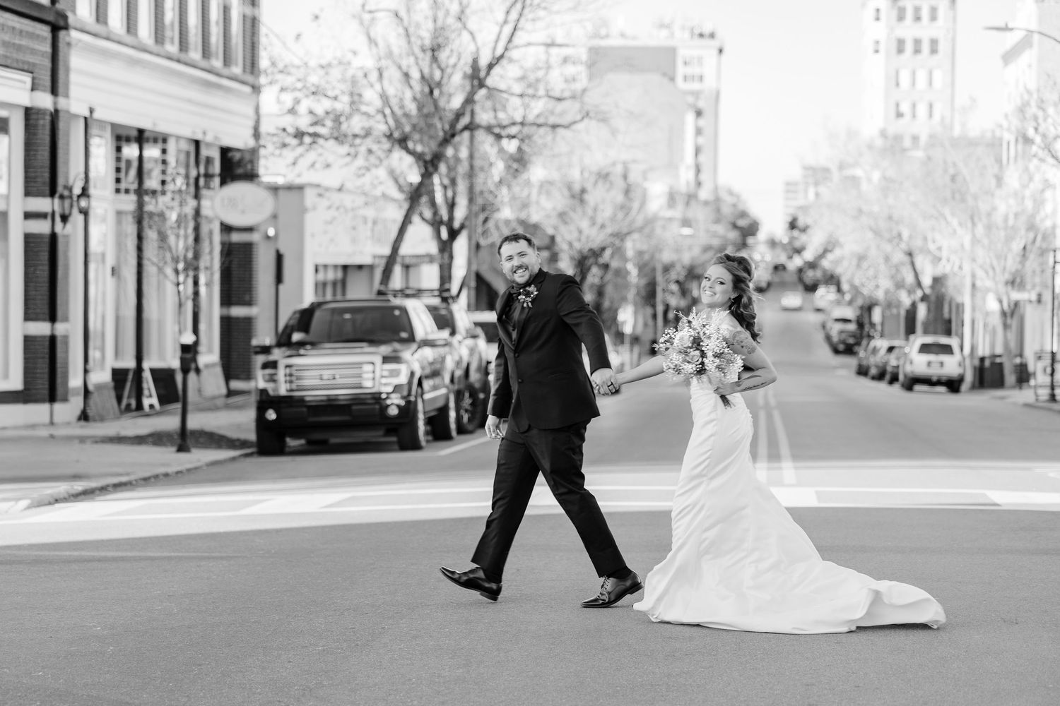 Black and white photo of newlyweds walking down a city street wedding groom bride wilmington North Carolina photographer light airy