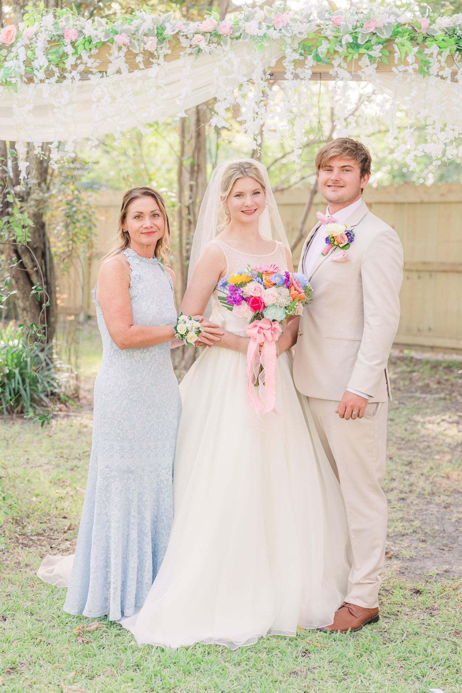 Wedding portrait under floral arch with colorful spring bouquet and formal attire wedding groom bride wilmington photographer light and airy
