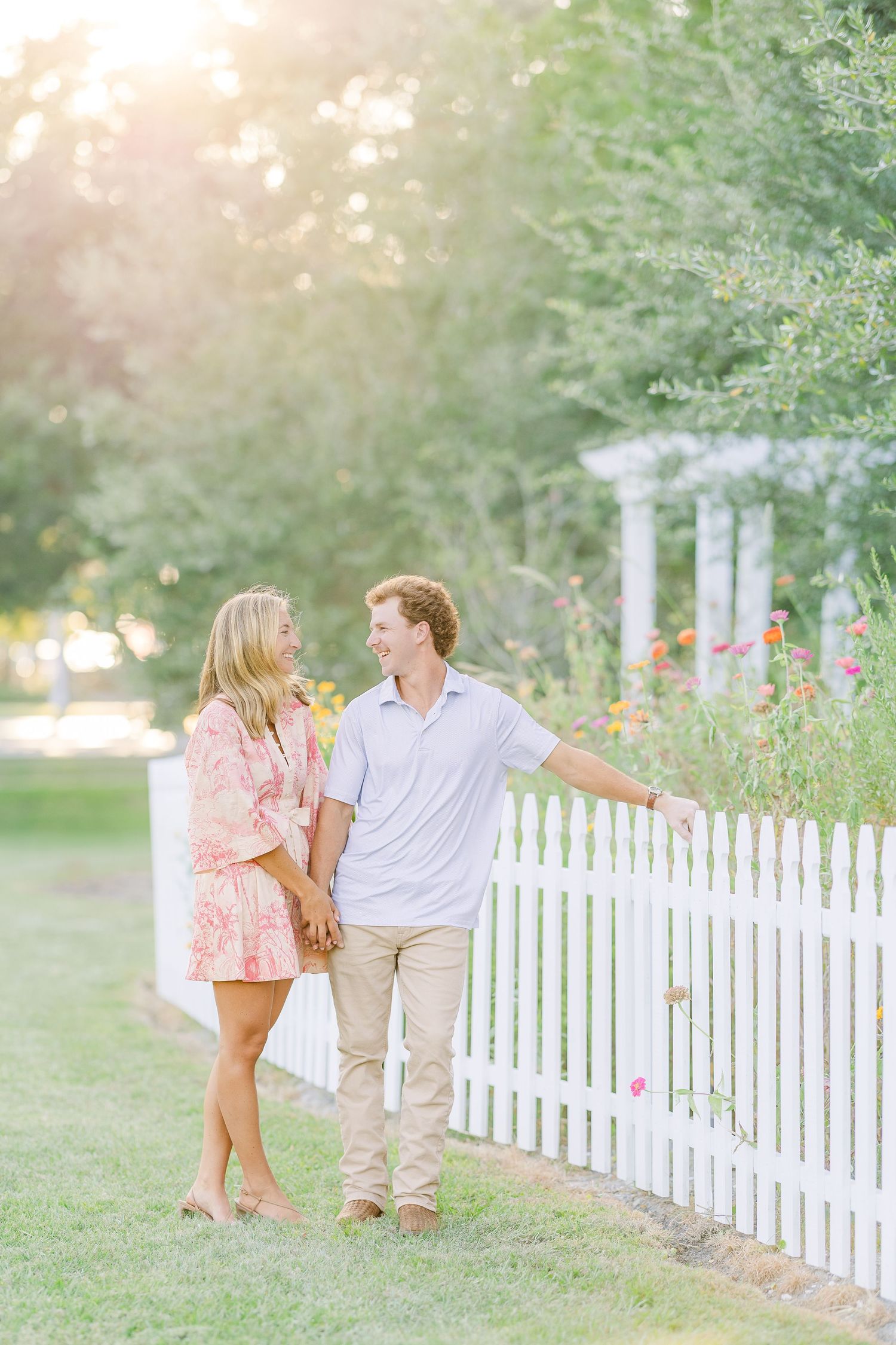 Sweet moments captured by white picket fence in garden setting during sunset.