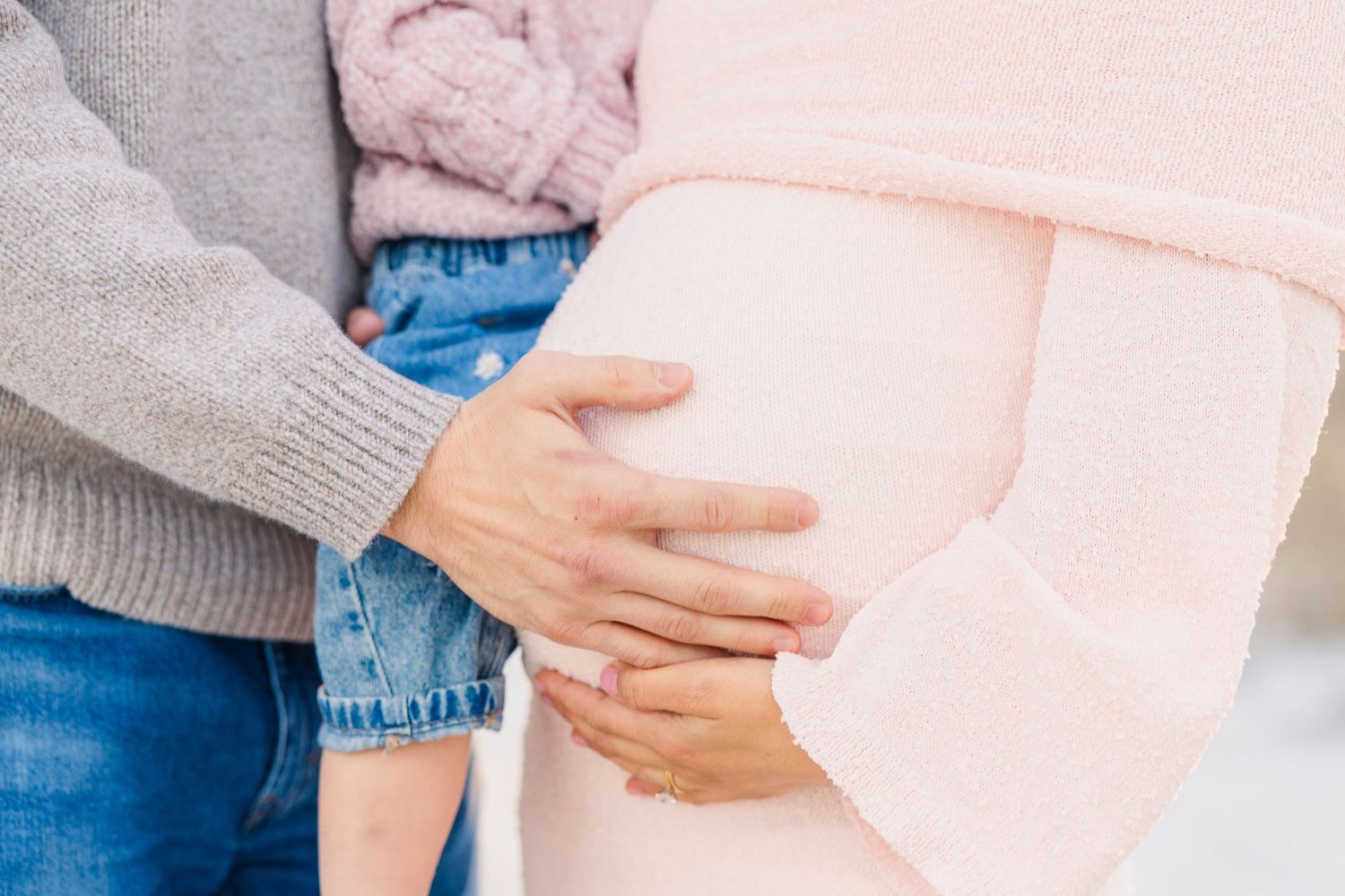 Close-up details of pink and denim clothing during beach family photoshoot.