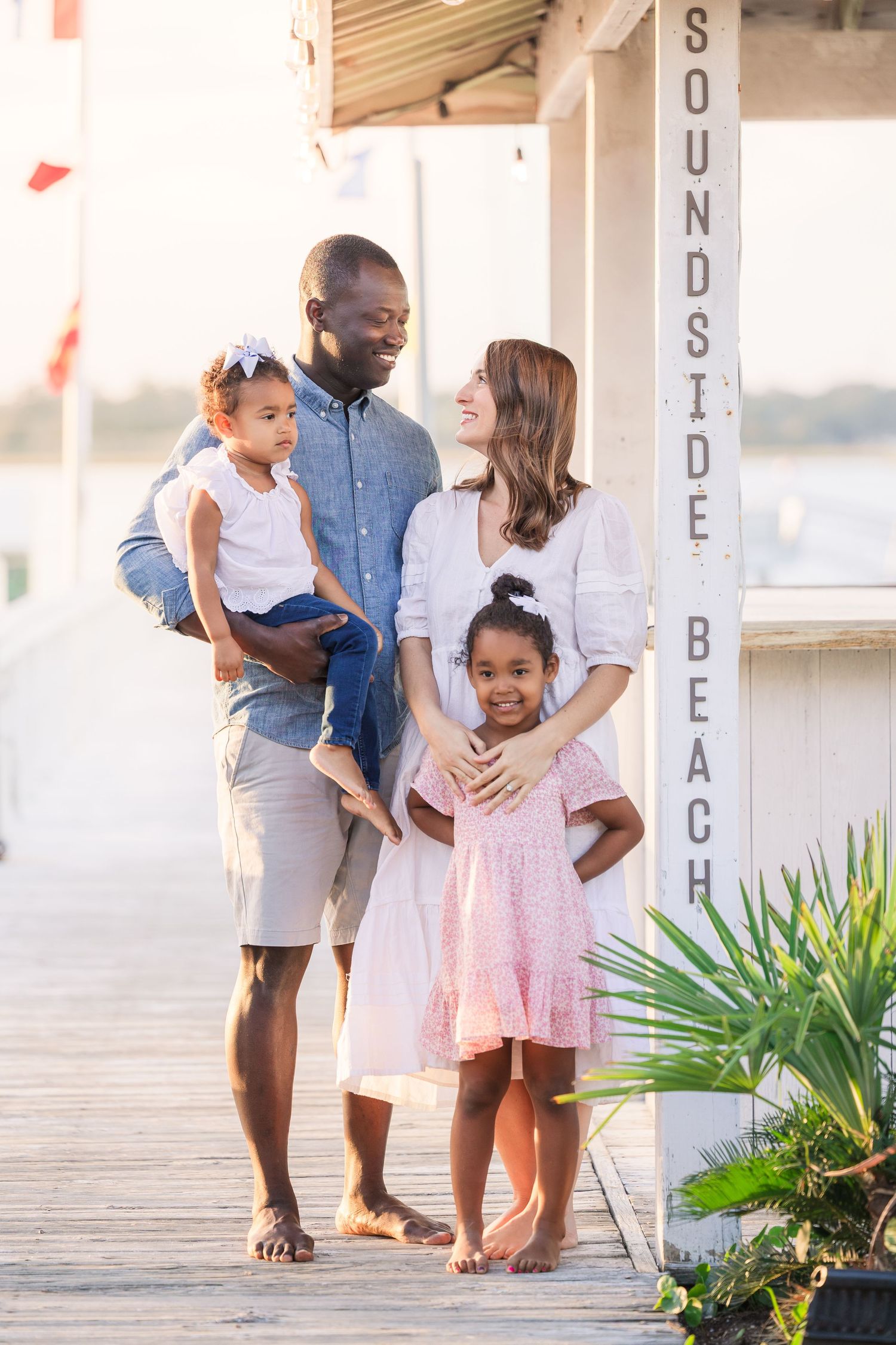 Family enjoying tender moments together on a beachside boardwalk.