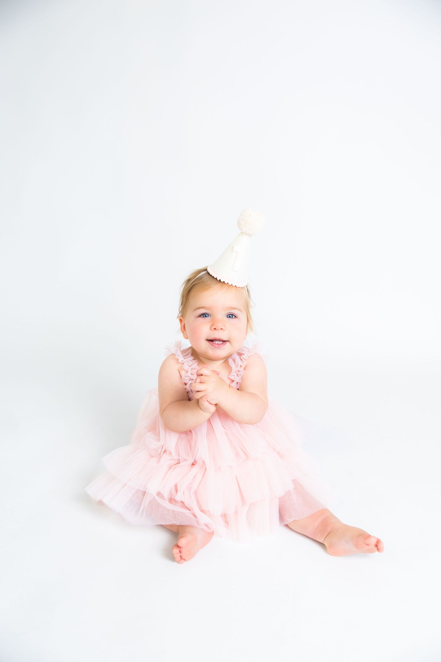 Baby in pink tulle dress crawling on white background.