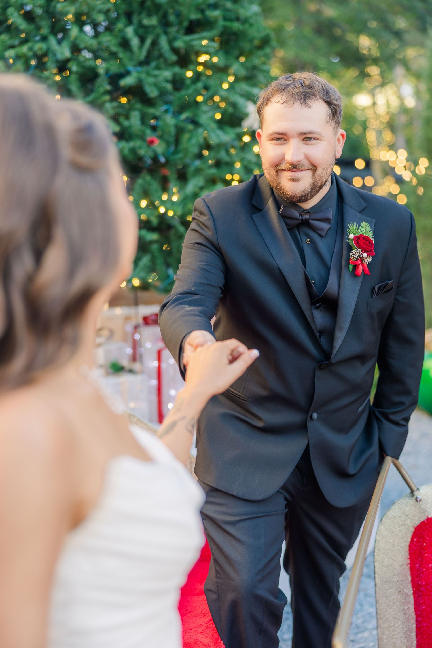 Elegant wedding photo with Christmas decor and twinkling lights in background.