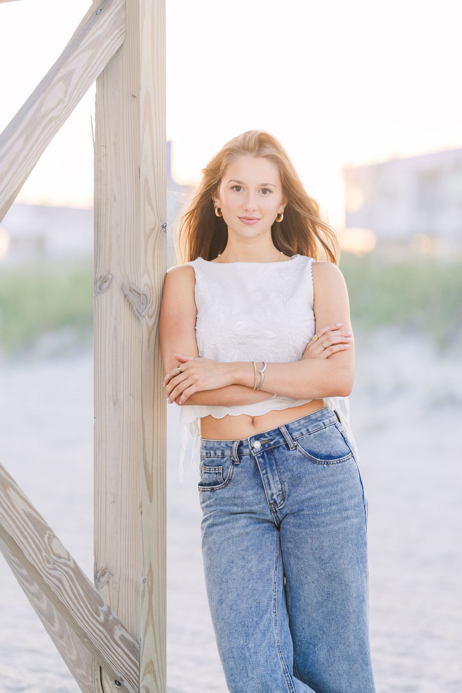 Casual beach portraits by wooden fence wearing denim and white tank top.