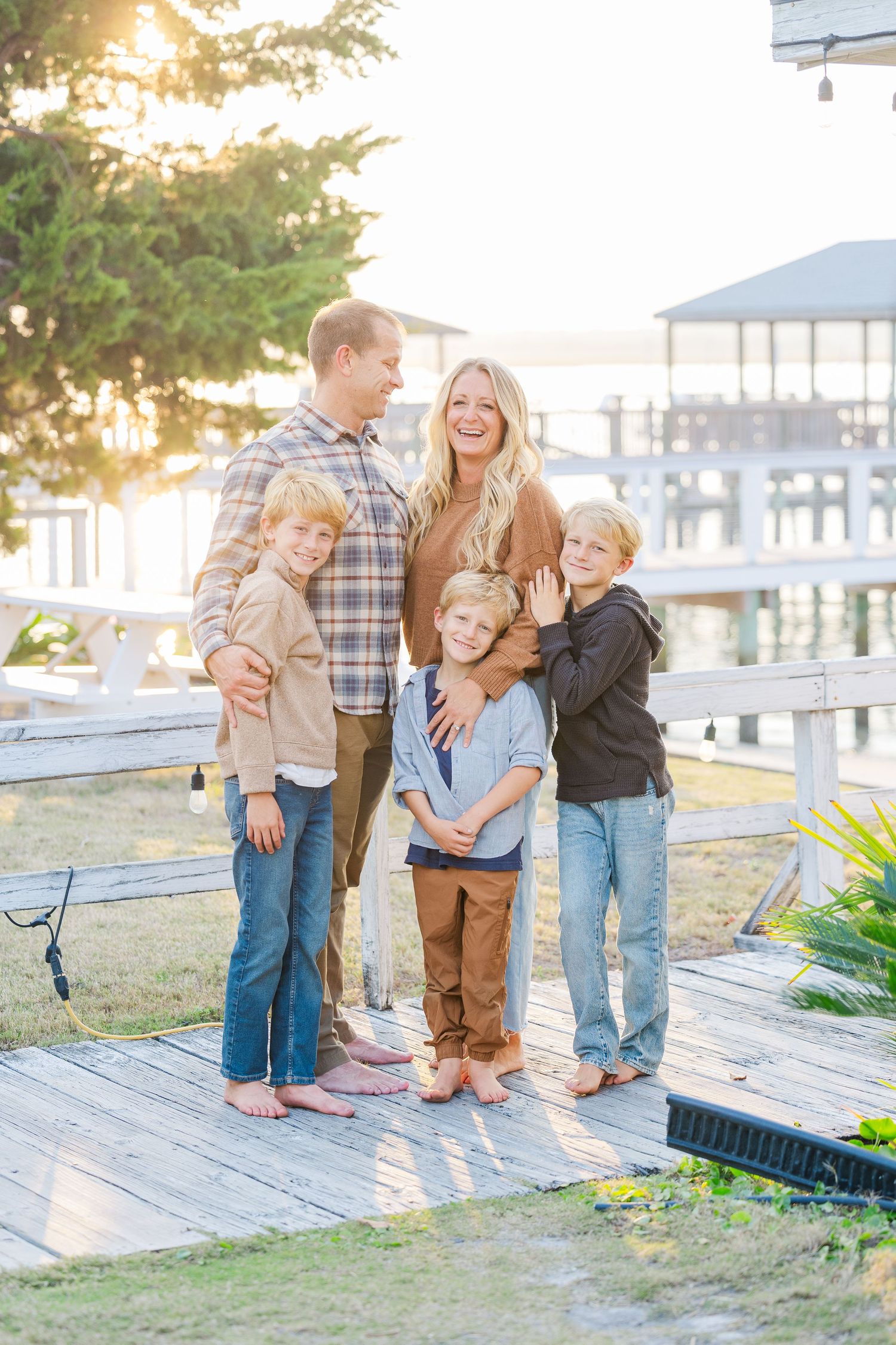 Family enjoys playful moments together on a wooden deck during golden hour sunset.