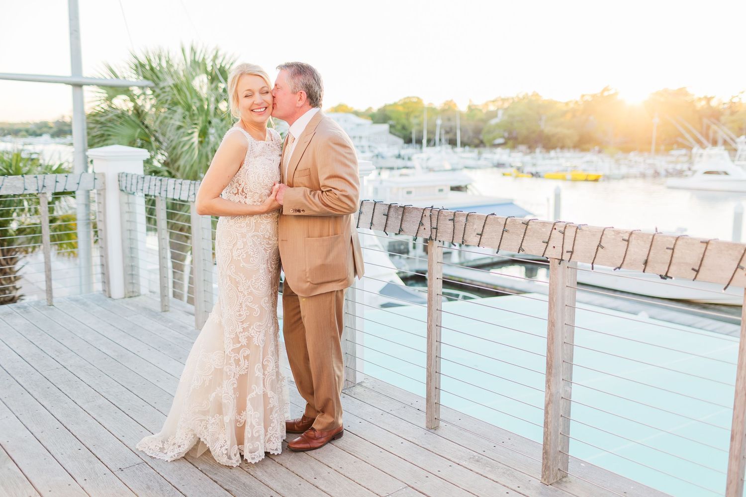 Scenic marina wedding venue with wooden deck and boats in the background during sunset.
